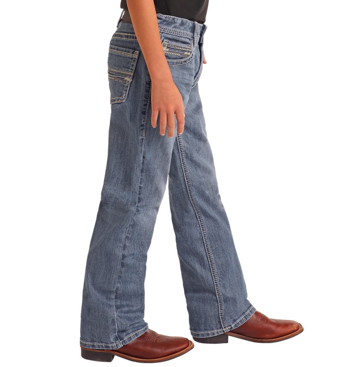 A boy in Rock & Roll Denim Boys' Regular Fit Two-Tone Embroidered Bootcut Jeans with white stitching and brown cowboy boots stands sideways against a plain white background.
