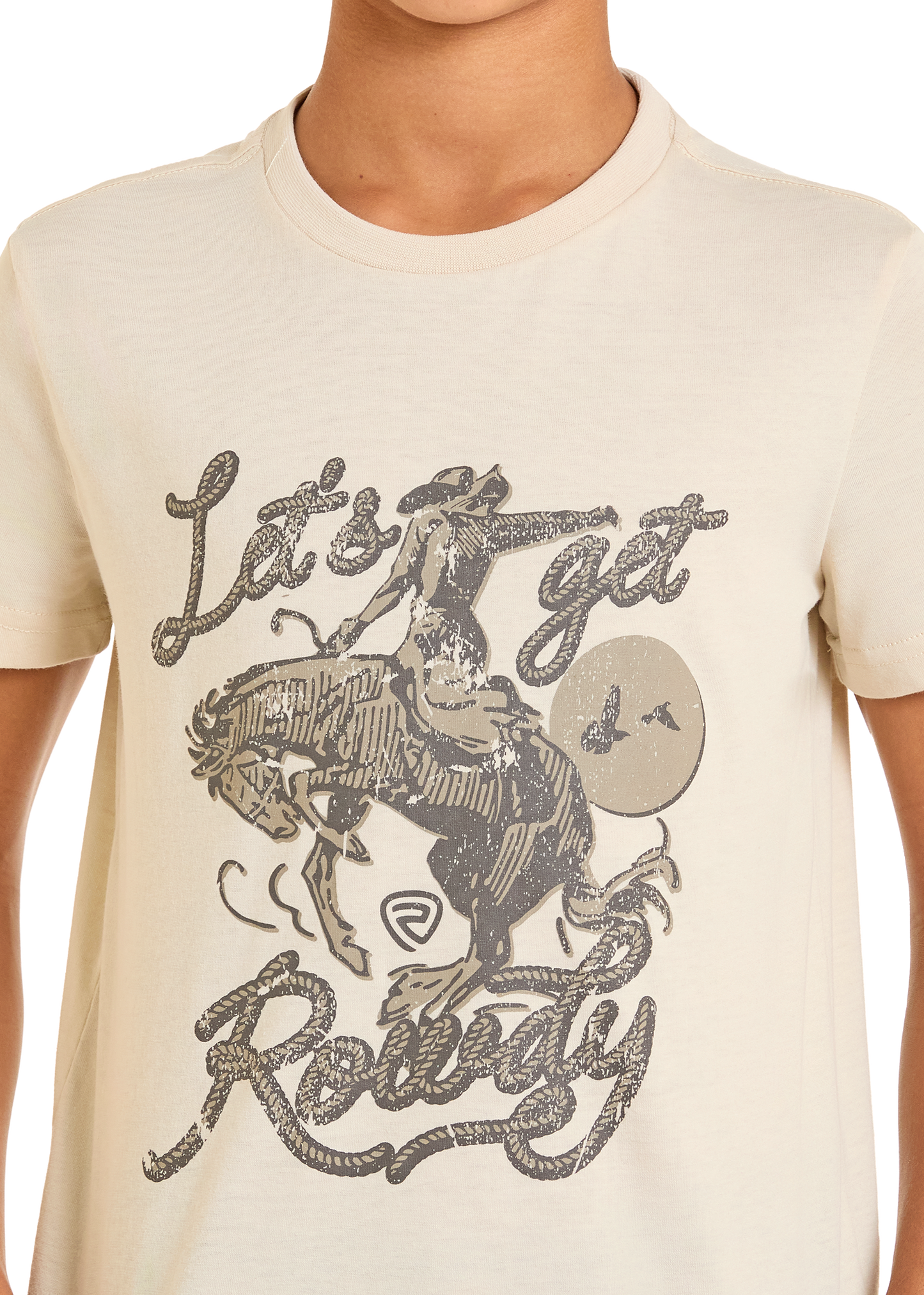 A person wears the Boys' Rowdy Graphic Tee by Rock & Roll Denim, featuring a cream color and bronco graphic with a rodeo cowboy, sunset, birds, and “Let’s Get Rowdy” in stylized lettering.