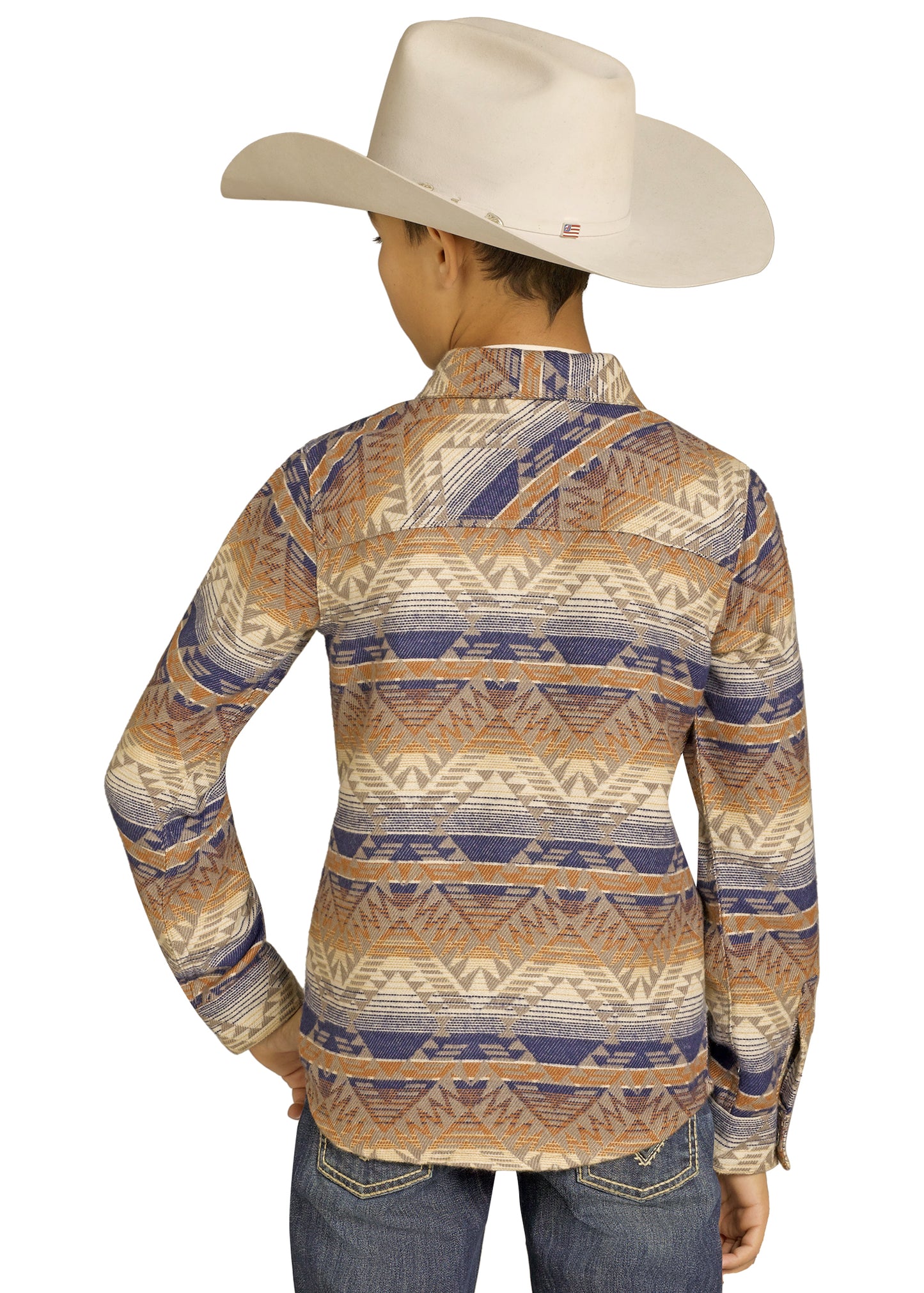 A person in blue jeans, a wide-brimmed beige cowboy hat, and a Rock & Roll Denim Kids' Brown Aztec Jacquard Shirt Jacket with brown, beige, and blue geometric designs stands facing away from the camera.