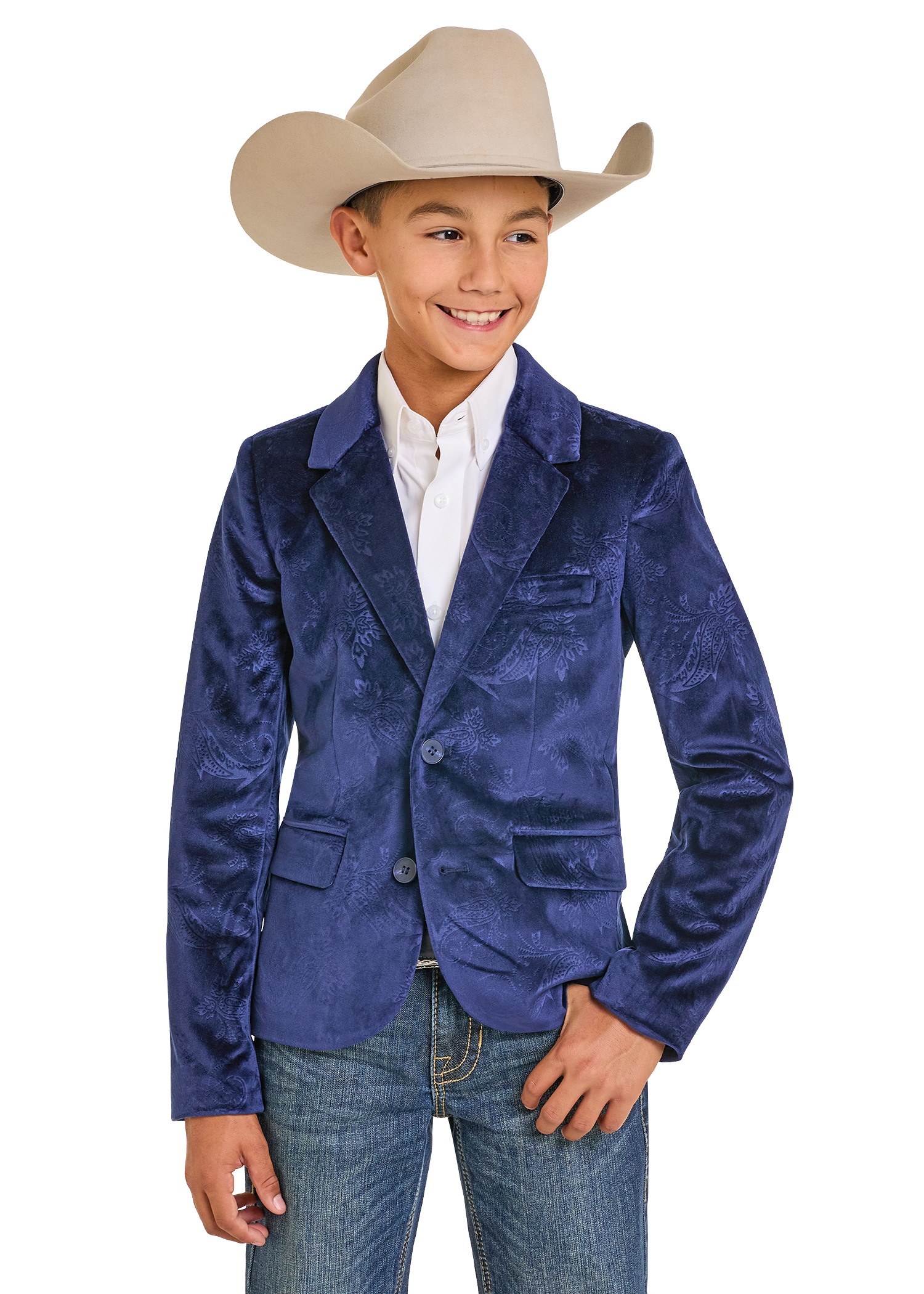 A smiling boy wears a tan cowboy hat, white dress shirt, Rock & Roll Denim Boys' Paisley Velvet Sports Coat, and blue jeans, standing with one hand in his pocket.