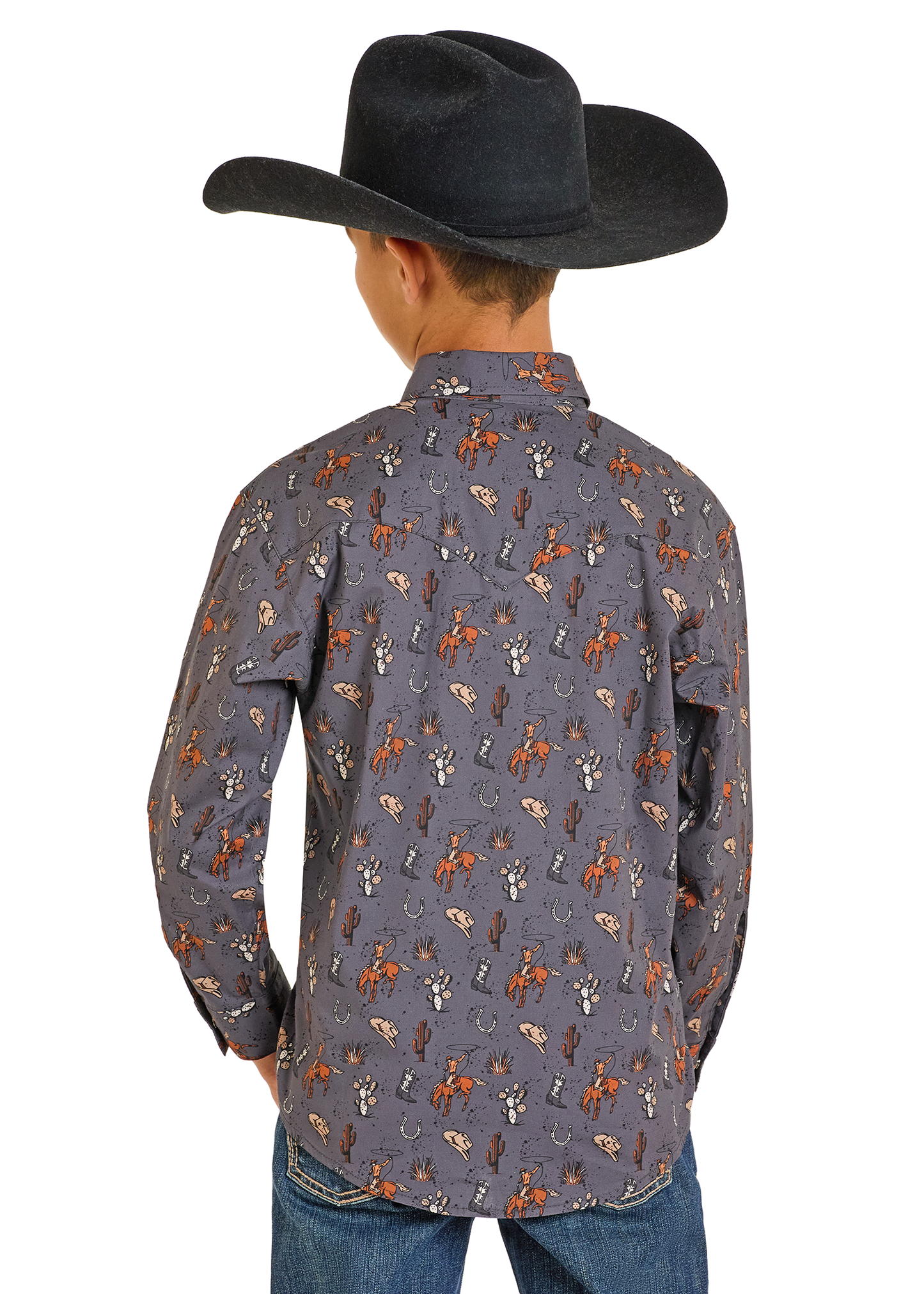 A child stands facing away, wearing a black cowboy hat, blue jeans, and a Rock & Roll Denim Boys' Cowboy Print Long Sleeve Snap Shirt.