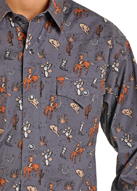 A person wears a gray, slim fit Boys' Cowboy Print Long Sleeve Snap Shirt by Rock & Roll Denim with an all-over cowboy, cacti, horseshoe, hat, and steer skull print. Only the torso and part of one arm are visible.