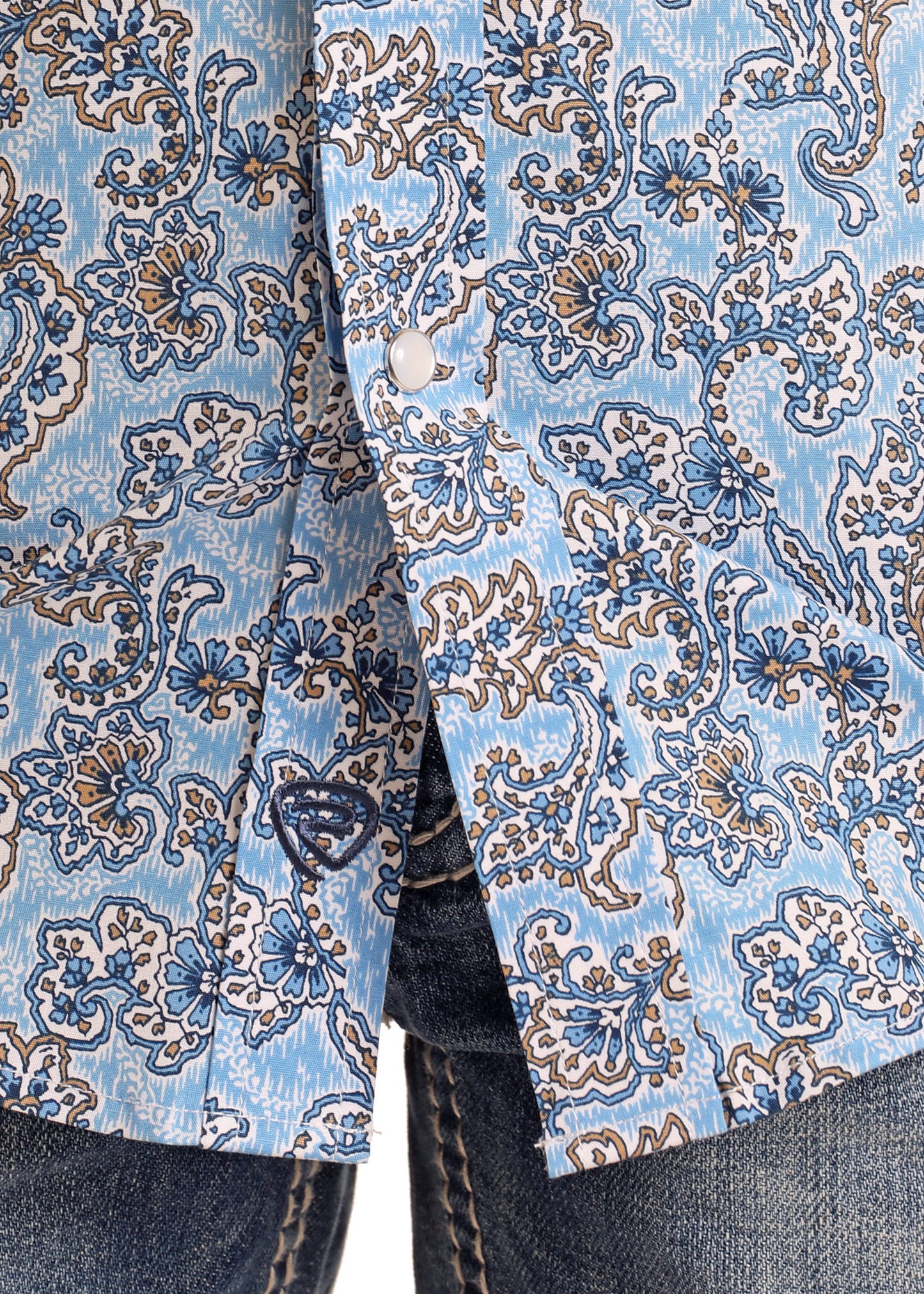 Close-up of the Rock & Roll Denim Boys' Blue Paisley Short Sleeve Snap Shirt, featuring a white and navy floral pattern, styled with blue jeans for a classic look.