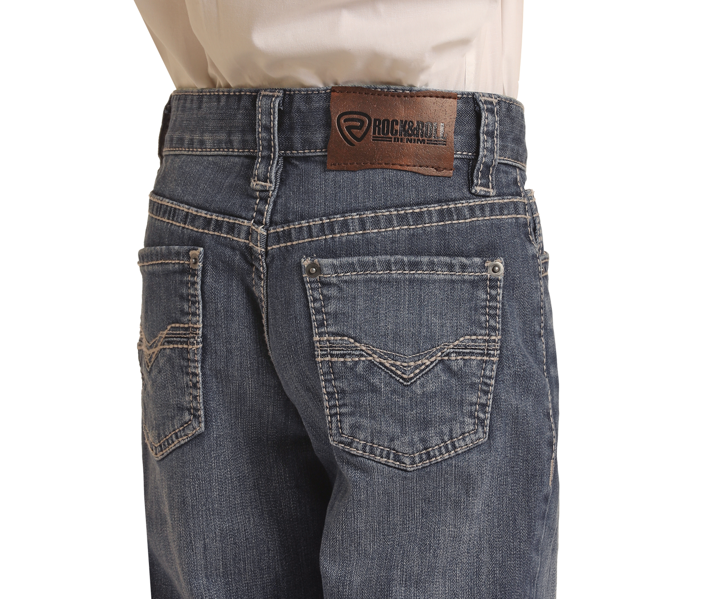 A boy is shown from the back wearing Rock & Roll Denim Boys' Regular Fit Bootcut Jeans with light grey top-stitching, a brown leather brand patch on the waistband, and two rear pockets with decorative stitching.