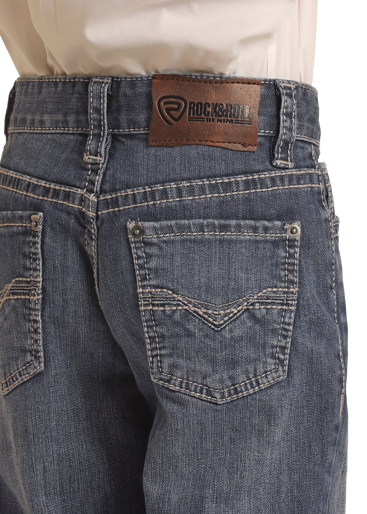 A boy is shown from the back wearing Rock & Roll Denim Boys' Regular Fit Bootcut Jeans with light grey top-stitching, a brown leather brand patch on the waistband, and two rear pockets with decorative stitching.