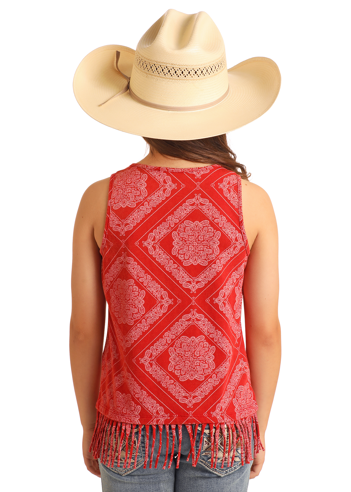 A person wearing a large beige cowboy hat and a Rock & Roll Denim Girls' Bandana Fringe Tank, featuring a sleeveless red design with white paisley print and fringe hem, stands facing away, displaying the tank's back along with blue jeans.