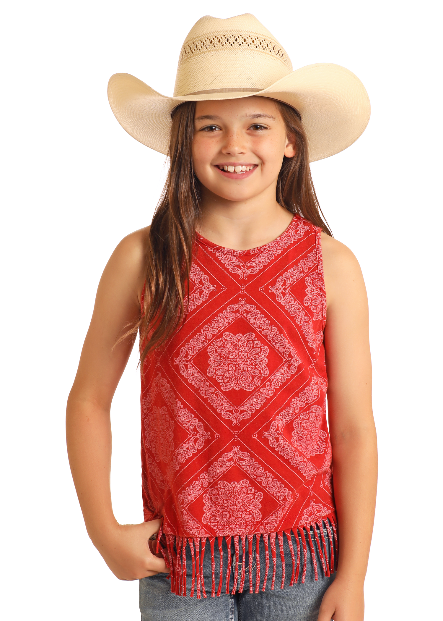 A smiling young girl wears the Rock & Roll Denim Girls' Bandana Fringe Tank—a sleeveless red bandana print top with a fringe hem—paired with blue jeans and a beige cowboy hat, standing against a white background.