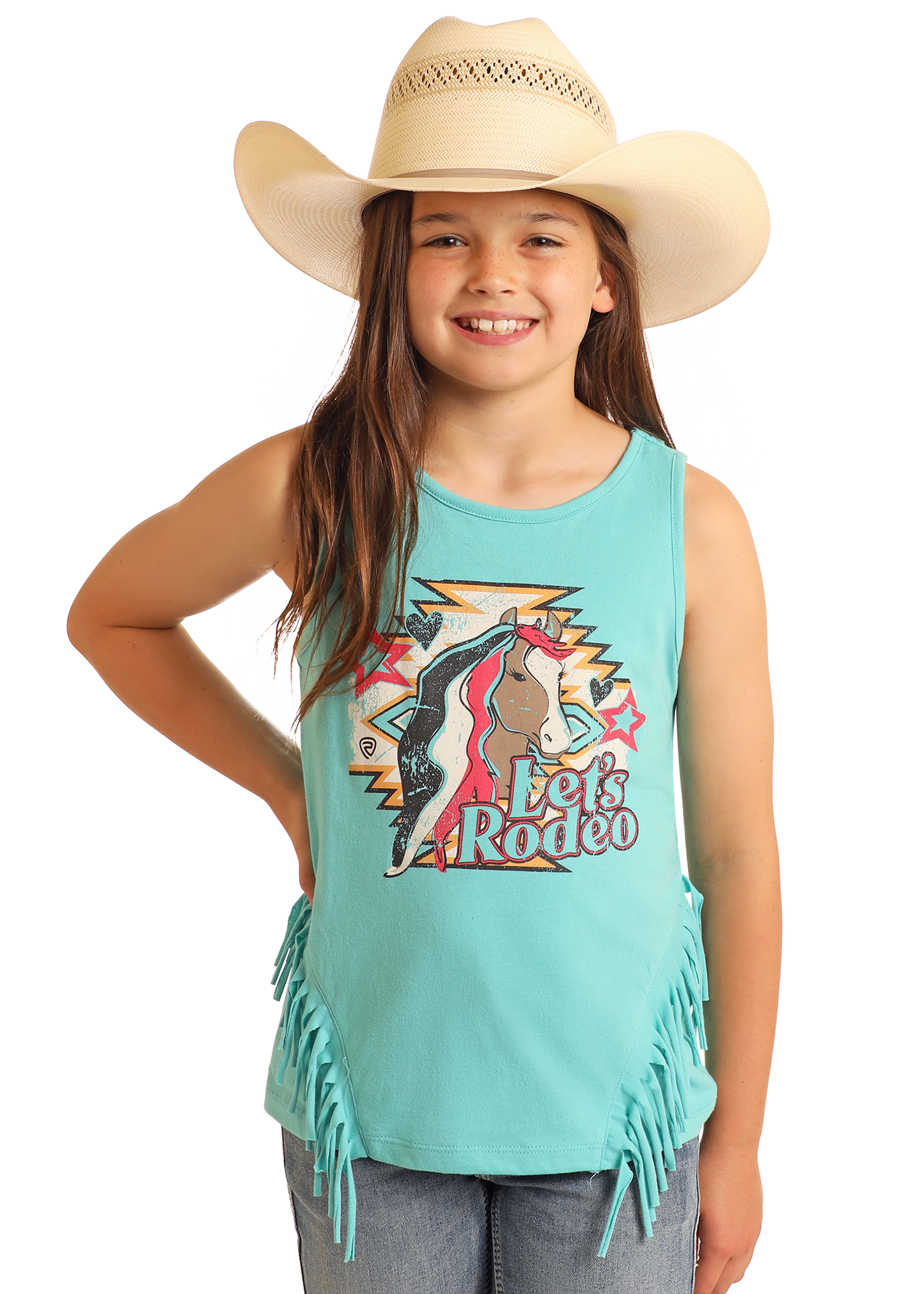 A smiling girl in a cowboy hat wears the Rock & Roll Denim Girls' Let's Rodeo Fringe Tank, featuring turquoise fabric, fringe details, and a colorful graphic, paired with blue jeans against a plain background.
