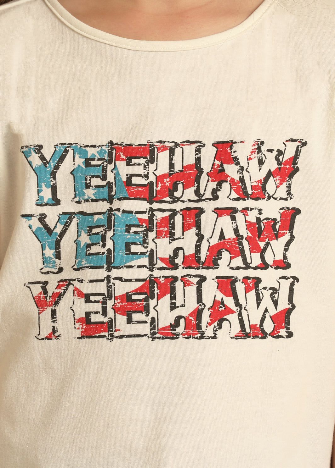 Show USA spirit in the Girls' American Flag Yeehaw Tee by Rock & Roll Denim—a cream t-shirt with YEEHAW printed three times in patriotic red, white, and blue distressed font. Perfect for celebrating America!.