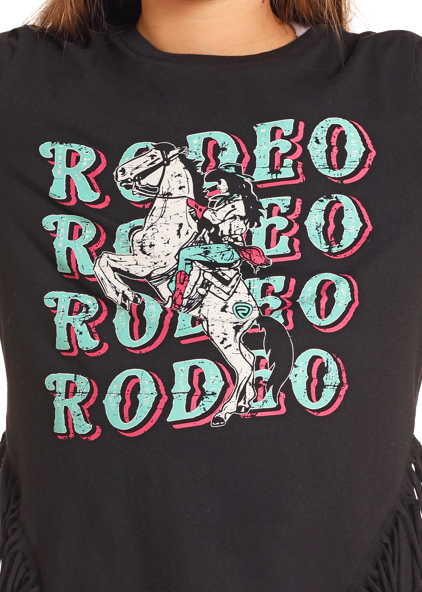 The Girls' Rodeo Fringe Long Sleeve Tee by Rock & Roll Denim features repeated "RODEO" text in teal and pink, plus a bold cowboy-on-horse graphic at the center.