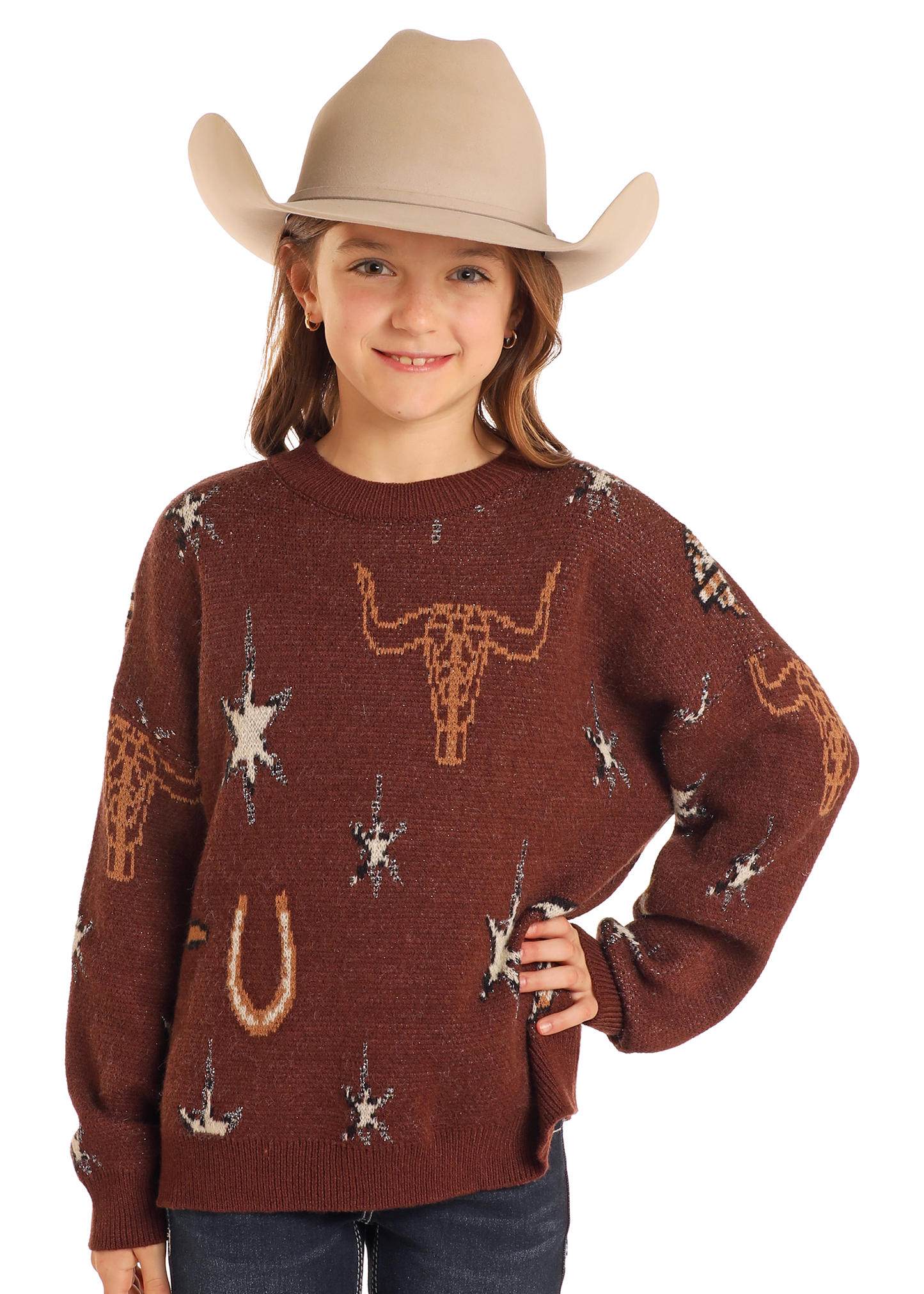 A young girl smiles with one hand on her hip, wearing the Rock & Roll Denim Girls' Western Print Sweater and a beige cowboy hat.
