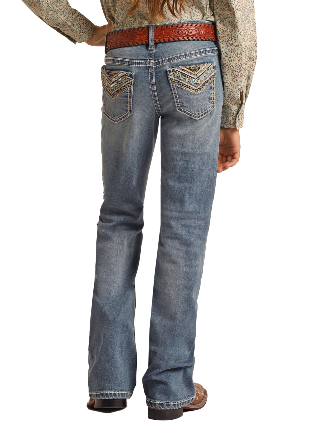 A person wearing a paisley shirt, Rock & Roll Denim Girls' Leopard Embroidered Pocket Bootcut Jeans, a brown woven belt, and brown shoes is shown from the back with one hand on their hip.