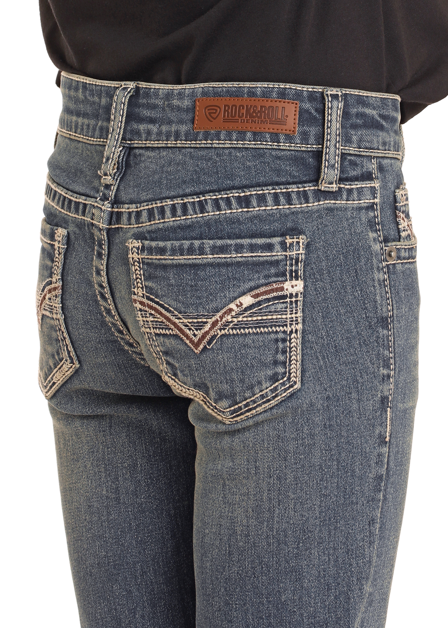 Close-up of a person wearing Girls' Mid Rise Extra Stretch Cowhide Stitch Bootcut Jeans, size 4, by Rock & Roll Denim, featuring decorative back pocket stitching and a brown leather brand patch on the waistband.