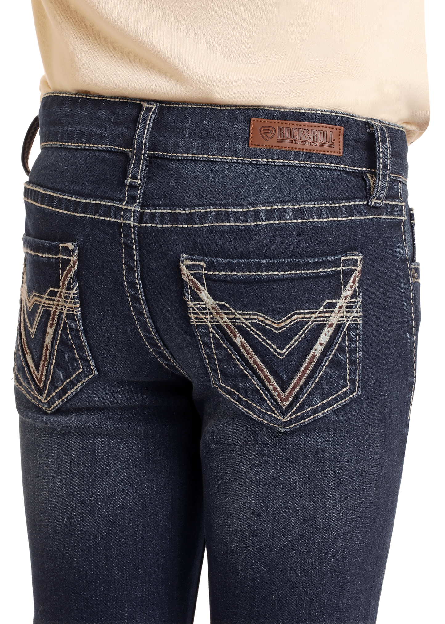 A close-up of the back of Rock & Roll Denim Girls' Mid Rise Cowhide V Stitch Bootcut Jeans features dark wash stretch denim, white stitching, decorative back pockets, and a brown leather brand patch on the waistband.