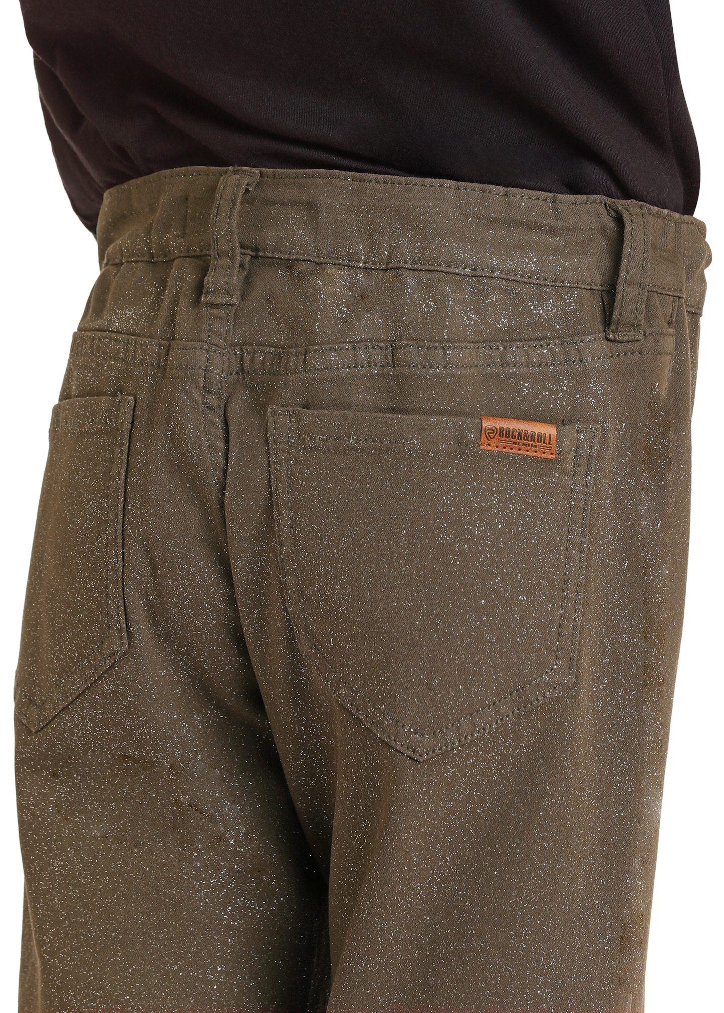 A close-up of a person wearing Rock & Roll Denim Girls' Glitter Flare Jeans in olive green, styled cowgirl-chic with a black shirt tucked in; the back pocket and a small brand label are visible.