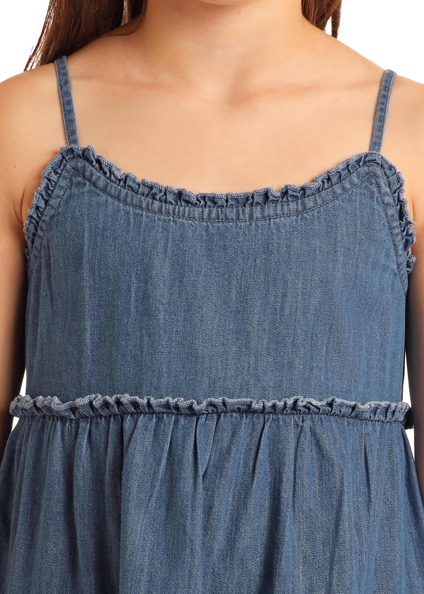 A close-up of the Rock & Roll Denim Girls' Denim Dress shows thin straps, ruffled neckline and waist details, and a stylish tiered skirt, highlighting its blue sleeveless design from chest to waist.