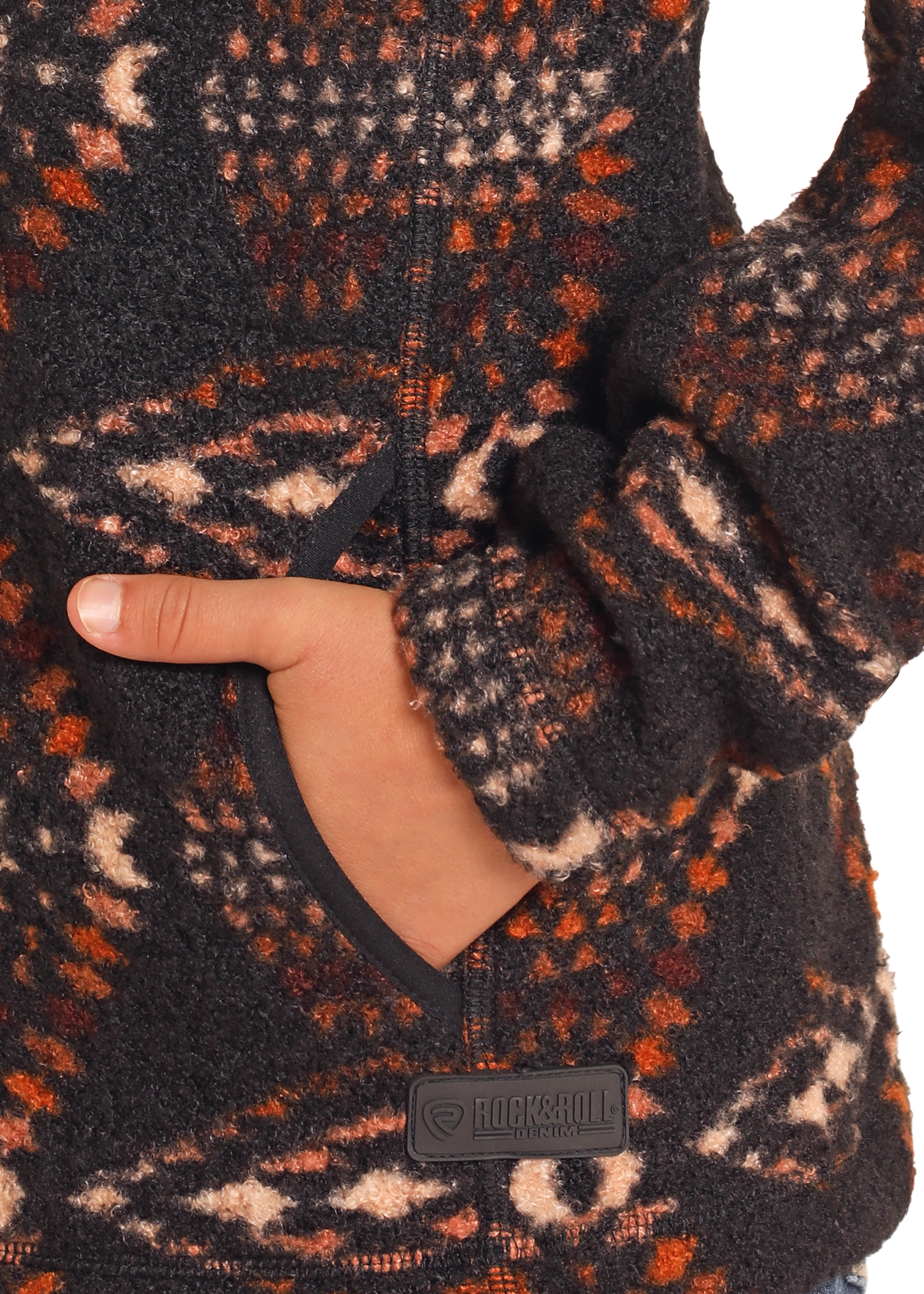 A close-up shows a hand in the pocket of the fuzzy Kids' Aztec Print Quarter Zip Pullover by Rock & Roll Denim, detailed with black, orange, and beige geometric patterns. The "Rock & Roll Denim" patch appears near the pocket.