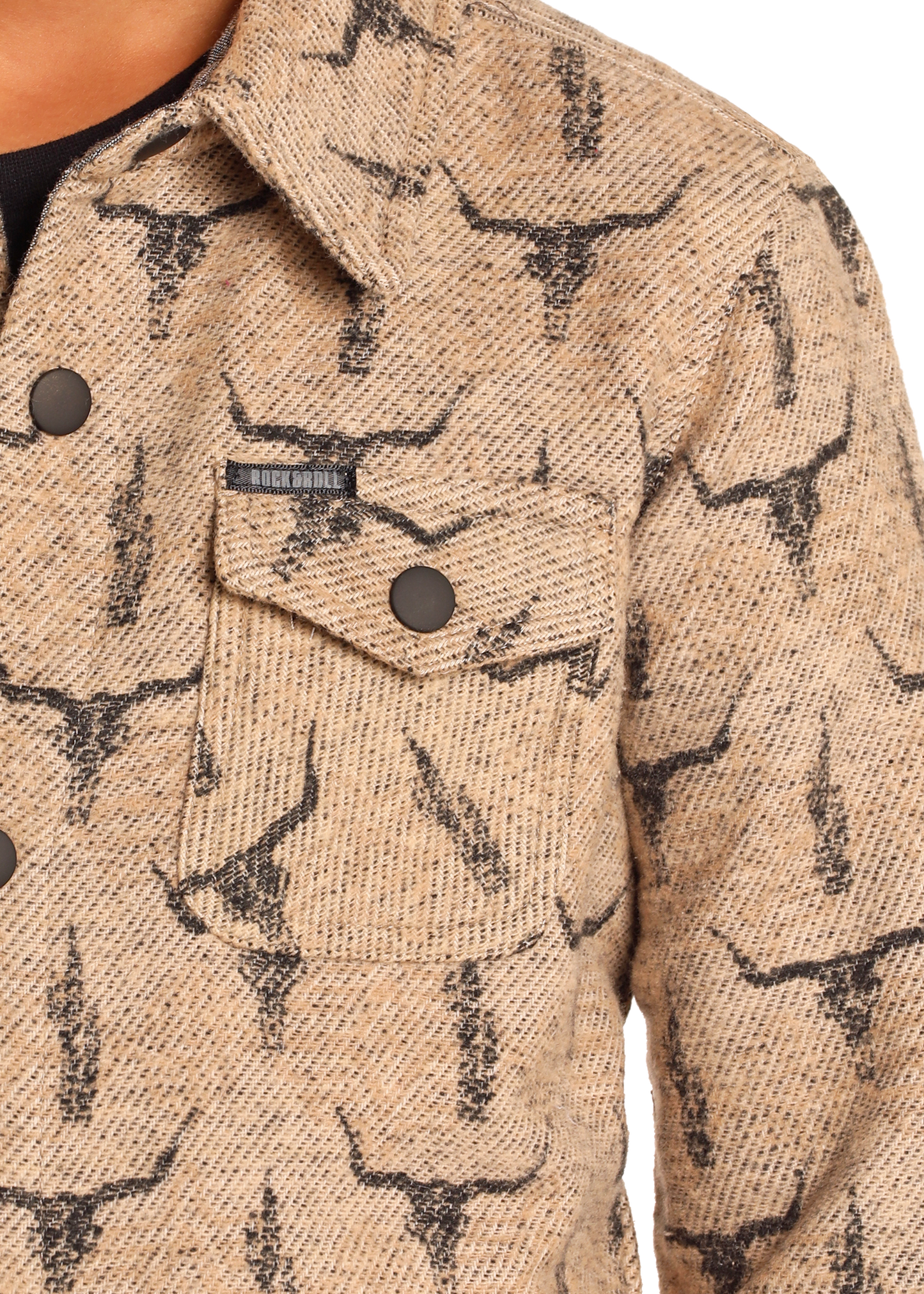 Close-up of the Rock & Roll Denim Kids' Steer Skull Shirt Jacket, showcasing a steer skull print, front flap pocket with two buttons, and a small rectangular label above the pocket on textured tan fabric.