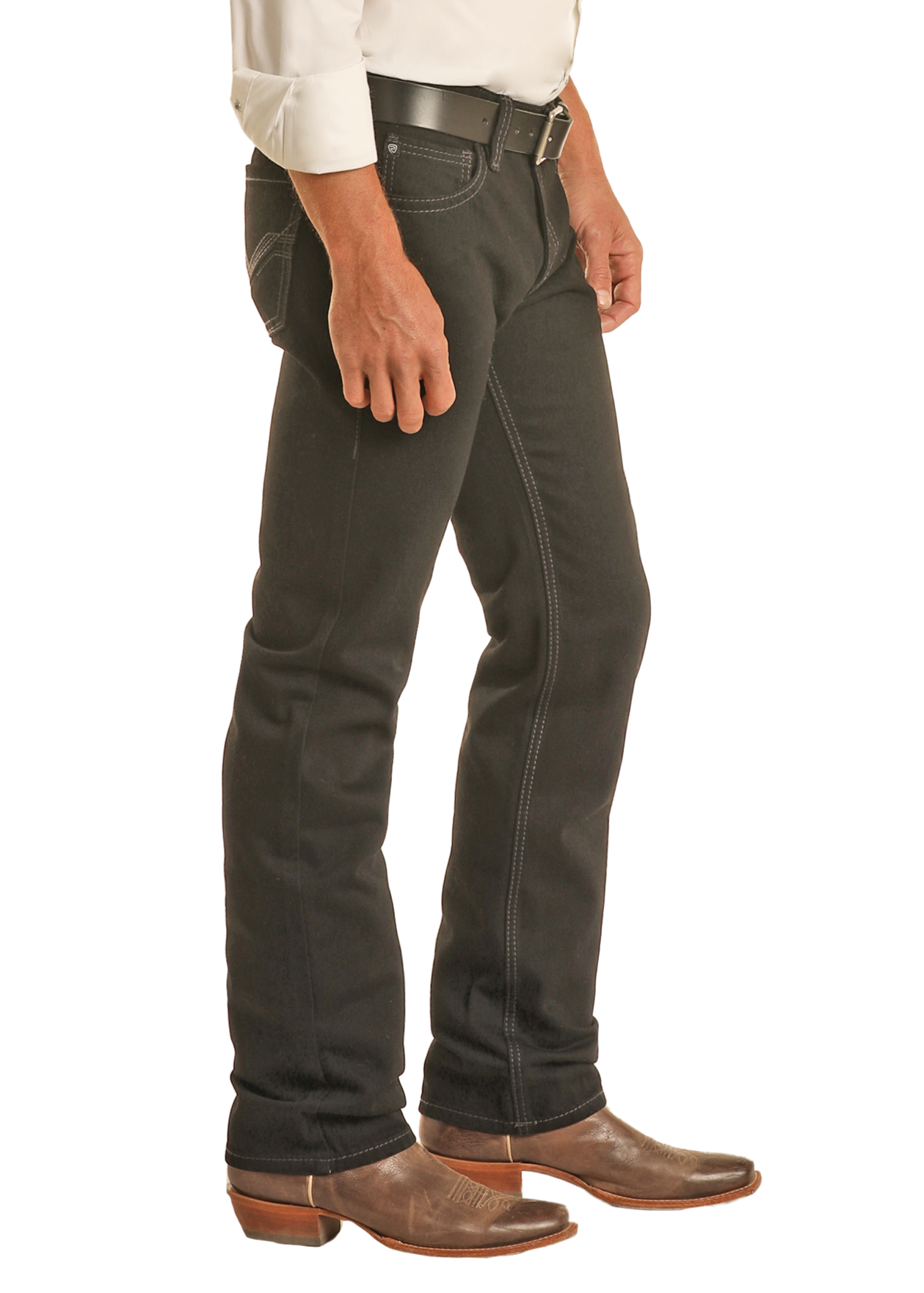 Wearing Rock & Roll Denim Black Slim Straight Jeans, a white long-sleeve shirt, black belt, and brown cowboy boots, a person stands sideways against a plain white background.