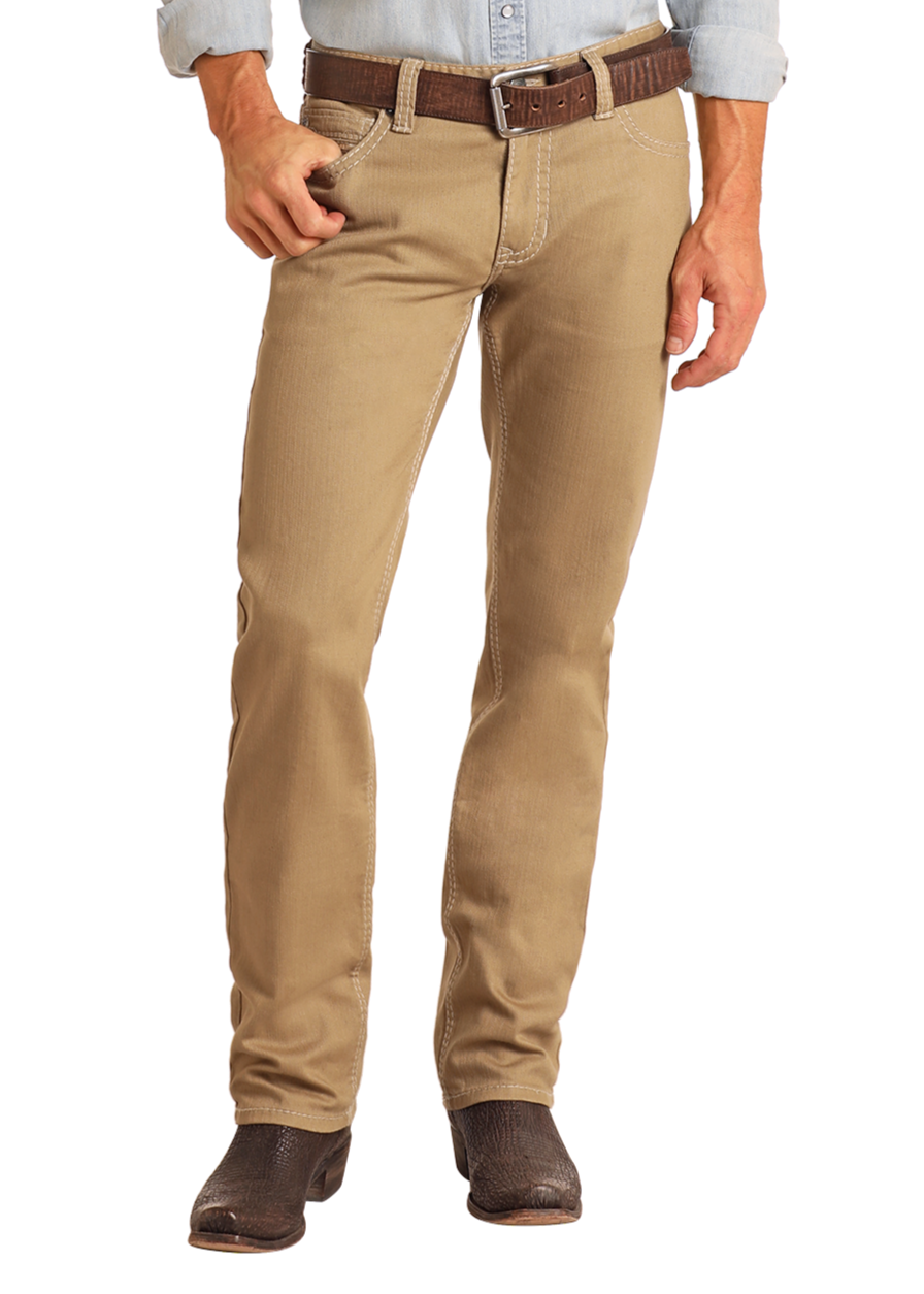 A person wearing Rock & Roll Denim Khaki Slim Straight Jeans, a brown belt, a light blue shirt, and dark brown boots stands against a plain white background with one hand in their pocket.