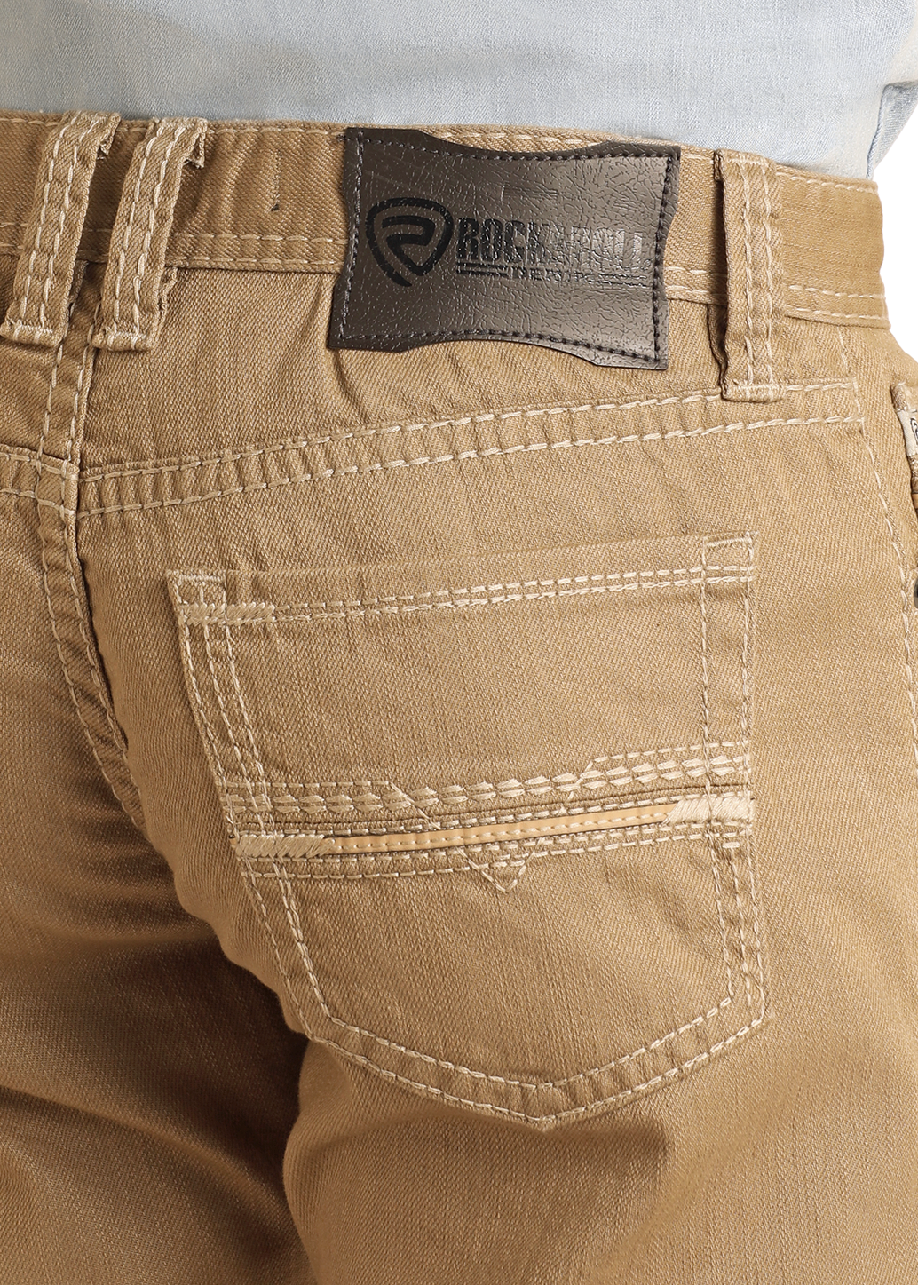 Close-up of the back of a person wearing Rock & Roll Denim Khaki Slim Straight Jeans with white stitching and a dark leather brand patch, styled with a light blue shirt tucked in for a classic slim fit look.