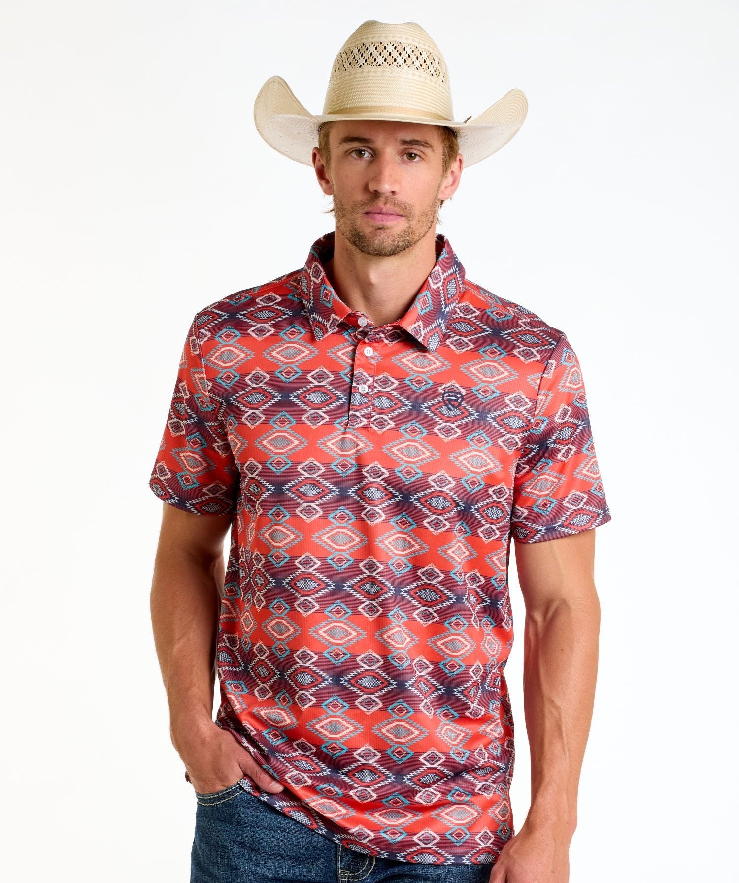 A man stands facing forward with one hand in his pocket, wearing the Rock & Roll Denim Aztec Vertical Striped Red Polo - S, a straw cowboy hat, and blue jeans against a white background.