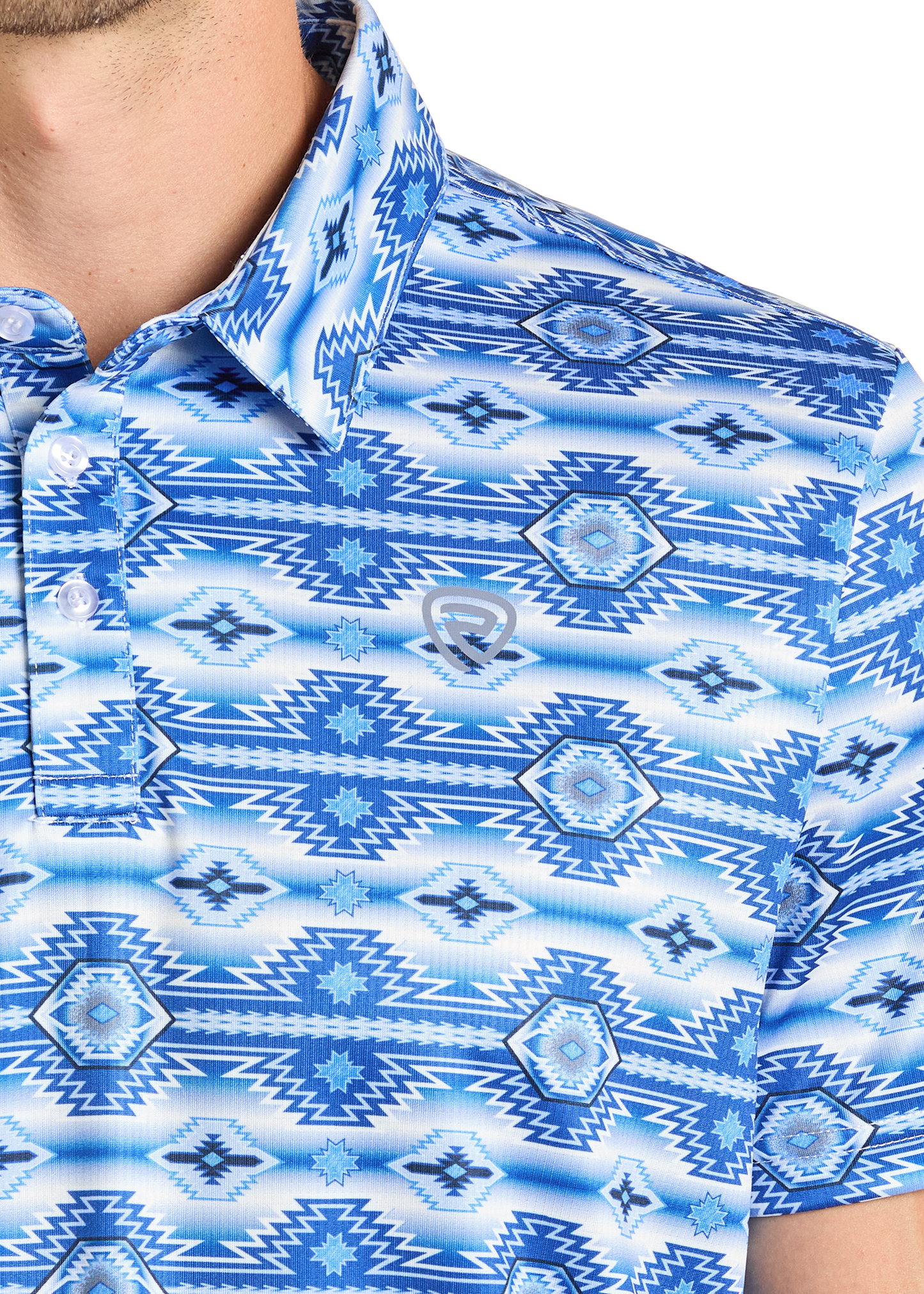 A close-up of the Rock & Roll Denim Aztec Blue Polo shows blue and white geometric patterns and an embroidered chest logo, focusing on the shoulder, chest, neck, and part of the face to highlight this stylish men’s casual polo.