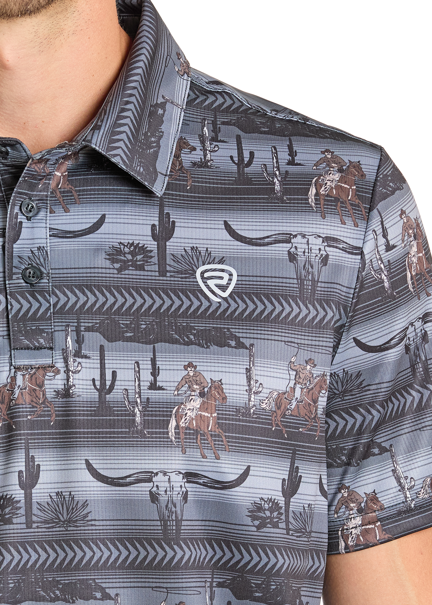 A close-up of a man's chest wearing the Rock & Roll Denim Longhorn Cowboy Polo, a regular fit button-up shirt featuring cowboys on horses, cacti, steer skulls, southwestern designs, and a small embroidered logo on the left side.