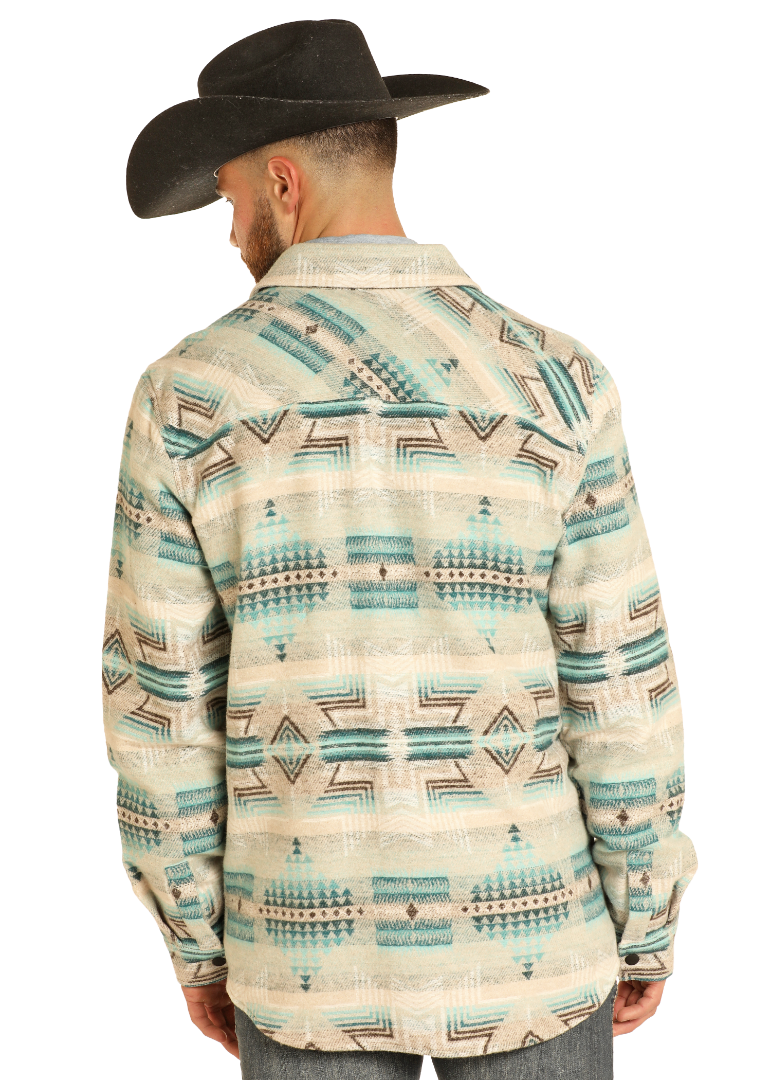 A man wearing a black cowboy hat and the Rock & Roll Denim Aztec Print Jacquard Shirt Jacket stands with his back to the camera, showcasing its cream fabric with teal and beige geometric designs against a plain background.