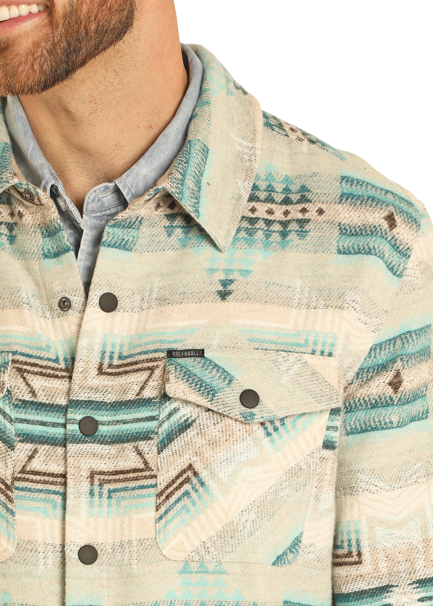 A man with a short beard wears a light blue button-up under the Rock & Roll Denim Aztec Print Jacquard Shirt Jacket, which features snap buttons and a geometric southwestern pattern. Only his lower face, neck, and upper torso are visible.