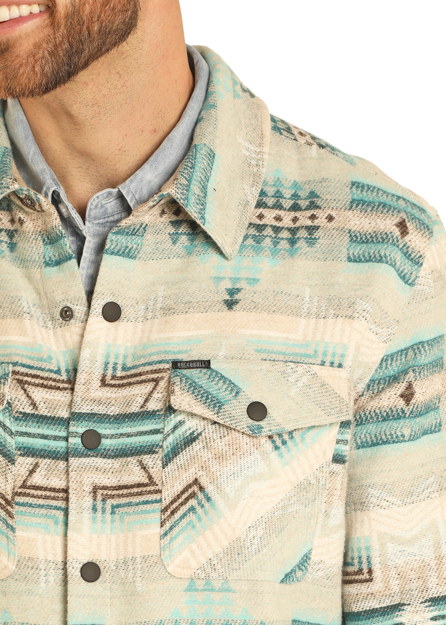 A man with a short beard wears a light blue button-up under the Rock & Roll Denim Aztec Print Jacquard Shirt Jacket, which features snap buttons and a geometric southwestern pattern. Only his lower face, neck, and upper torso are visible.