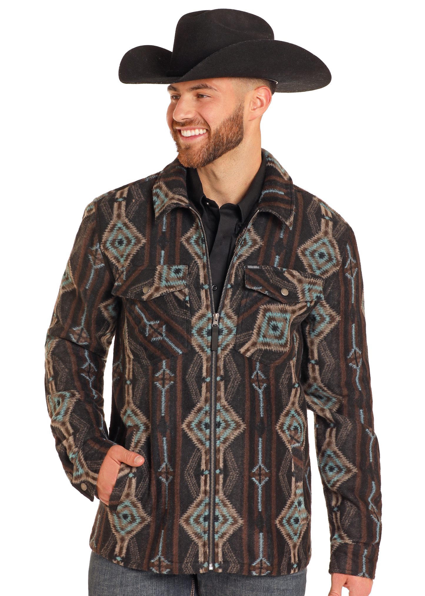 A man wearing a black cowboy hat and a Rock & Roll Denim Aztec Print Brushed Jacquard Zip Up Jacket poses with a smile, one hand in his pocket, against a plain white background.