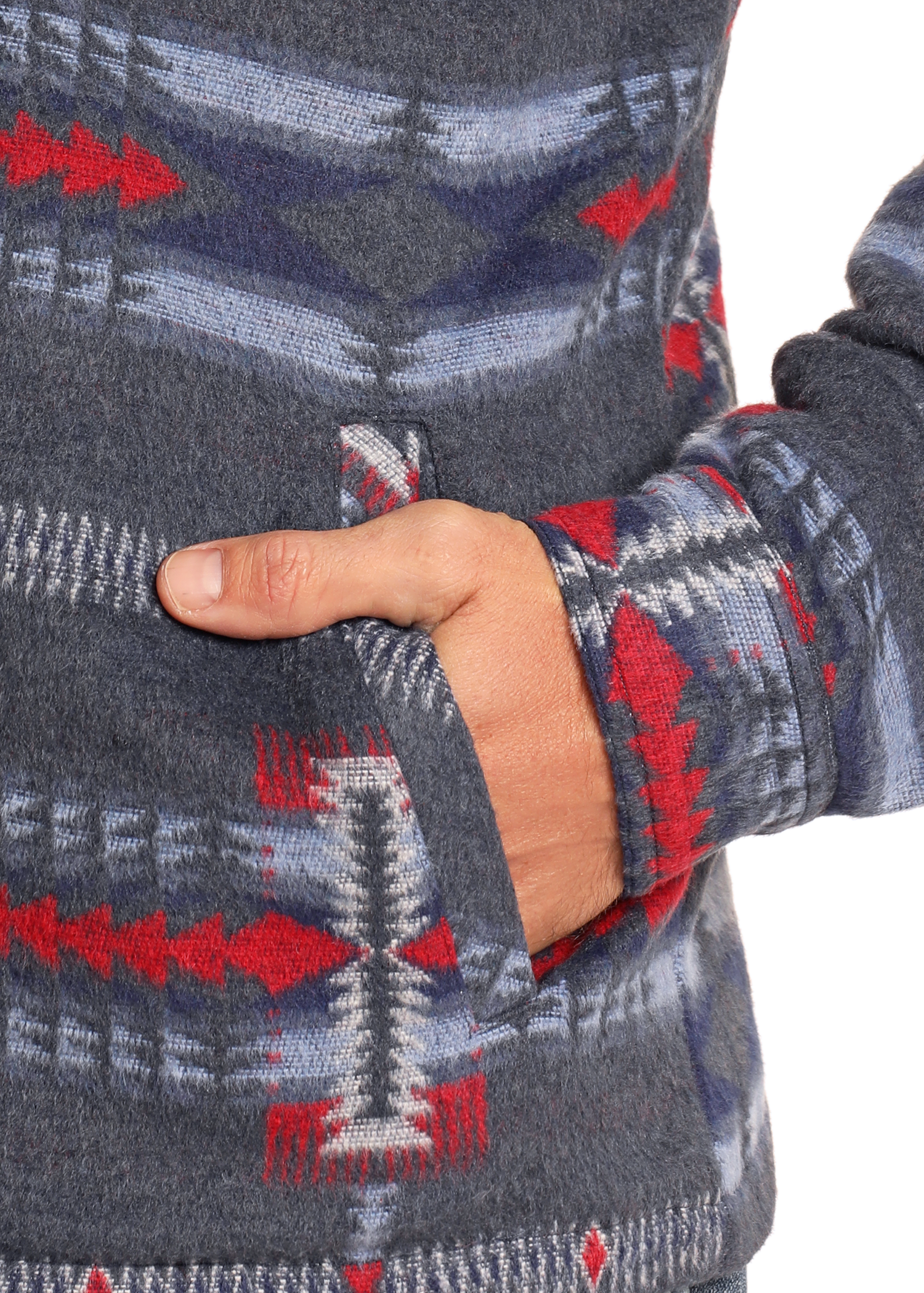 A close-up of a hand partially tucked into the pocket of the Rock & Roll Denim Blue Aztec Brushed Jacquard Zip Up Jacket, featuring red, blue, and white geometric patterns.