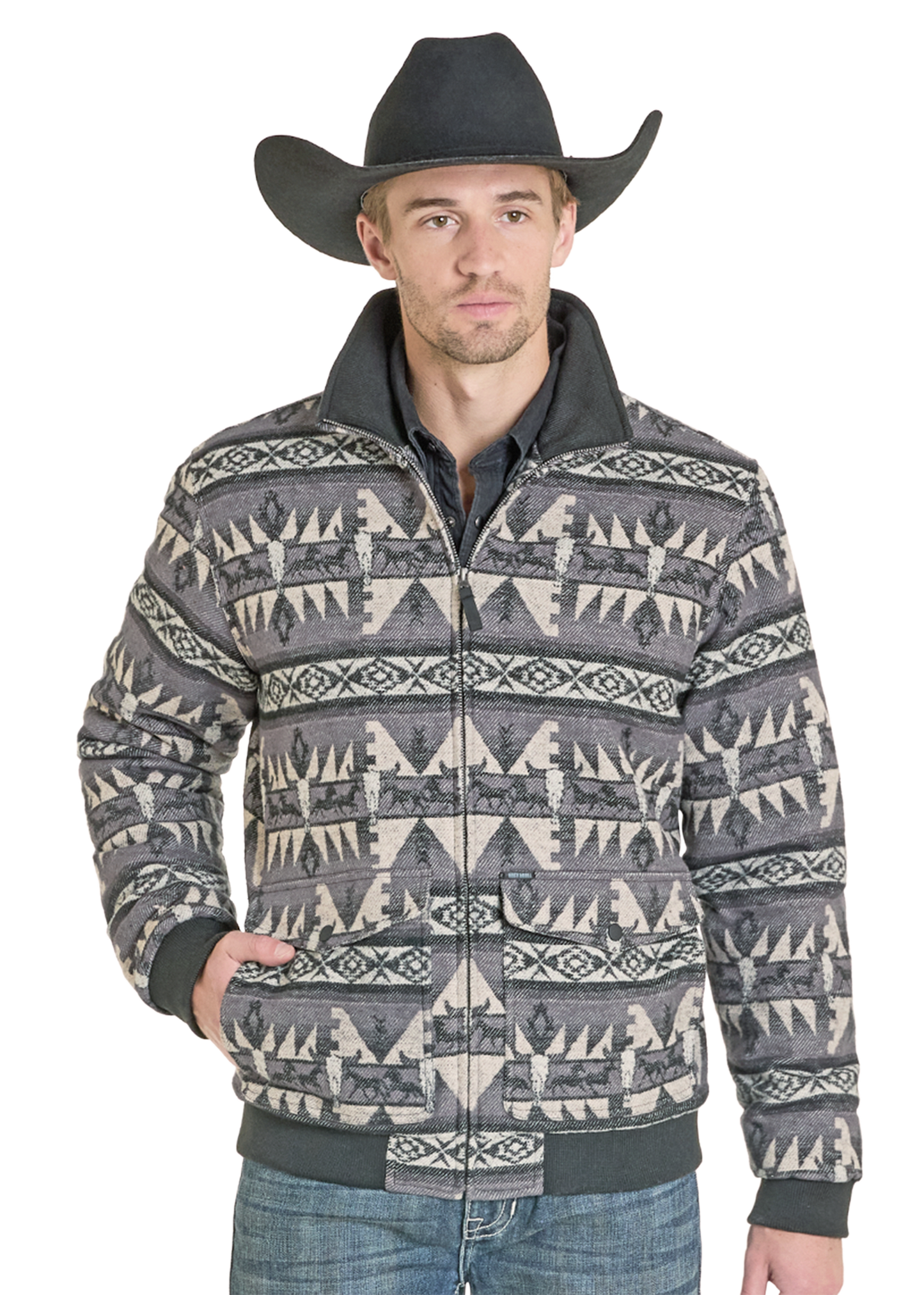A man in a black cowboy hat and blue jeans stands with one hand in his pocket, wearing the Rock & Roll Denim Jacquard Aztec Horse Bomber Jacket with striking geometric designs, his expression neutral against a plain background.
