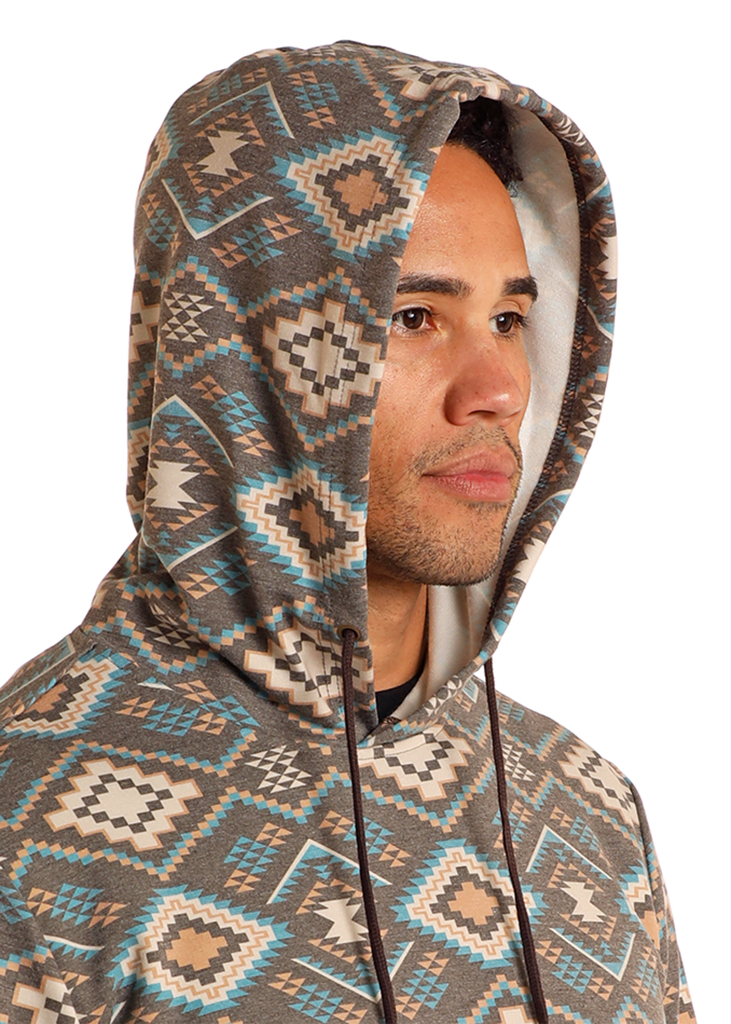 A person in the Rock & Roll Denim Brown Aztec Print Hoodie featuring geometric shapes in brown, beige, blue, and white looks to the side with the hood up against a plain white background.