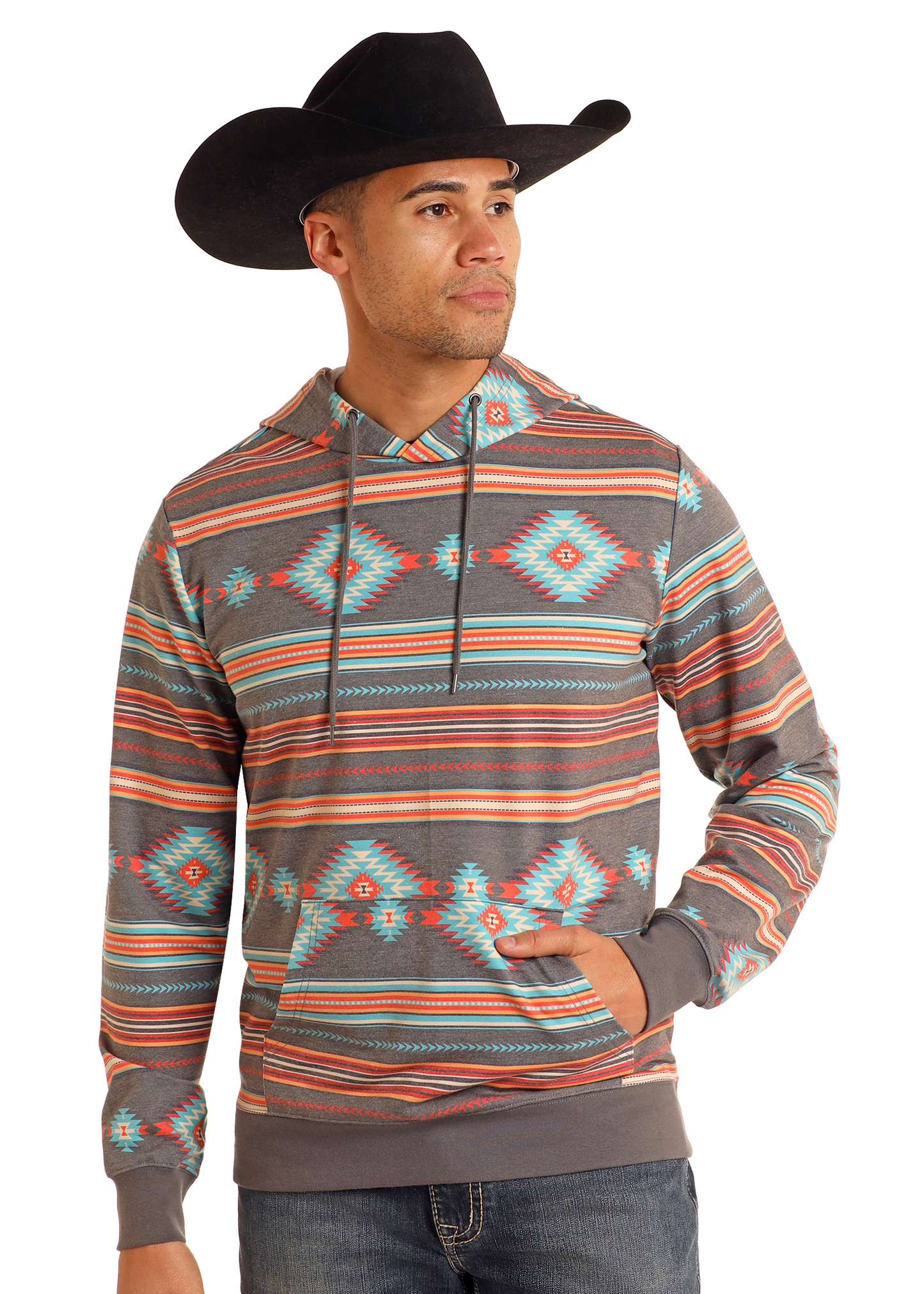 A man wearing a black cowboy hat and a Rock & Roll Denim Grey Aztec Print Hoodie featuring vibrant orange, teal, and gray geometric designs stands with one hand in his pocket, looking to the side.