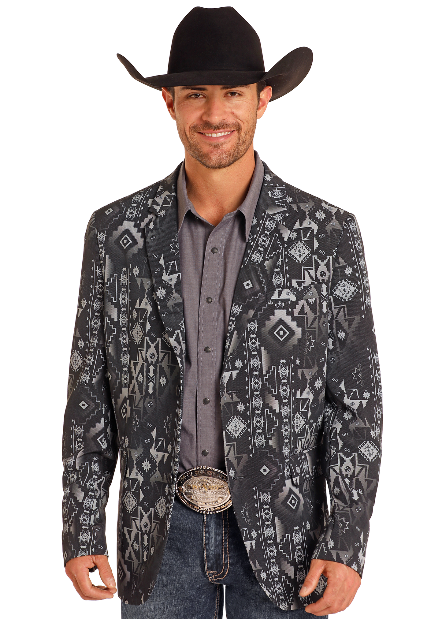 A man smiles while wearing a Rock & Roll Denim Black Aztec Sport Coat featuring southwestern designs, paired with a gray shirt, blue jeans, black cowboy hat, and a large belt buckle.