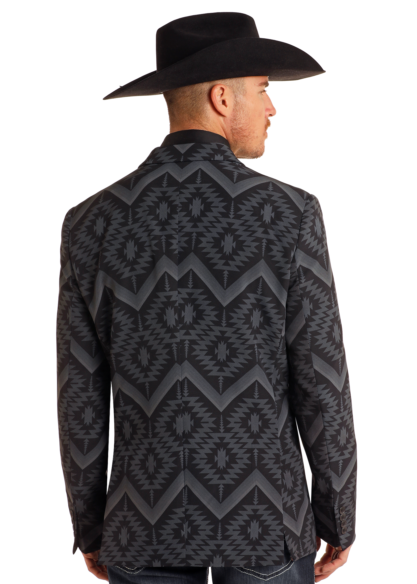 A man in a black cowboy hat and a Rock & Roll Denim Black Southwest Print Sport Coat with bold geometric designs stands facing away, showcasing the striking back of his outfit.