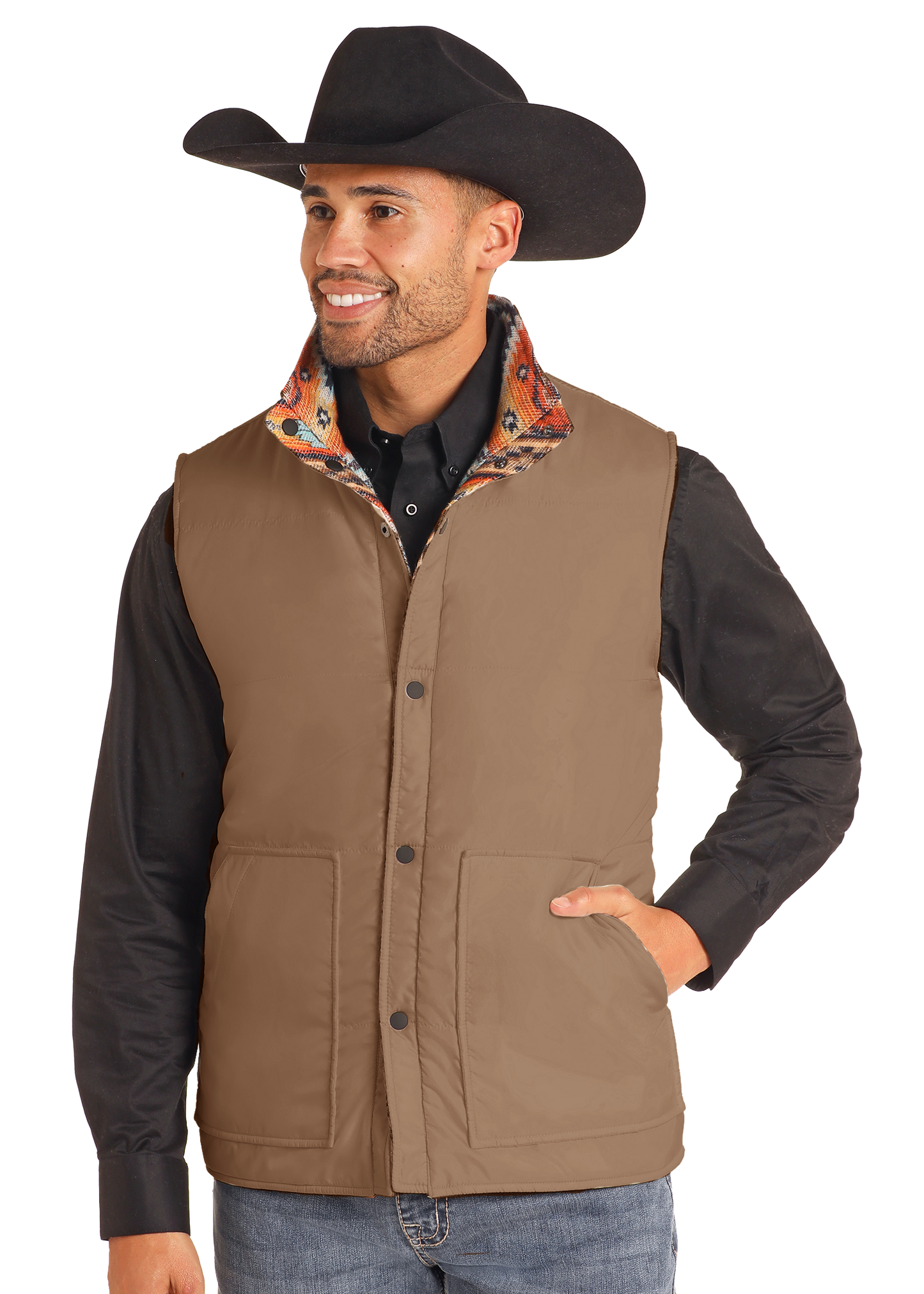 A smiling man stands with one hand in his pocket, wearing a black cowboy hat, a black shirt, and the Reversible Aztec Jacquard Vest by Rock & Roll Denim, effortlessly highlighting classic men's style against a plain background.