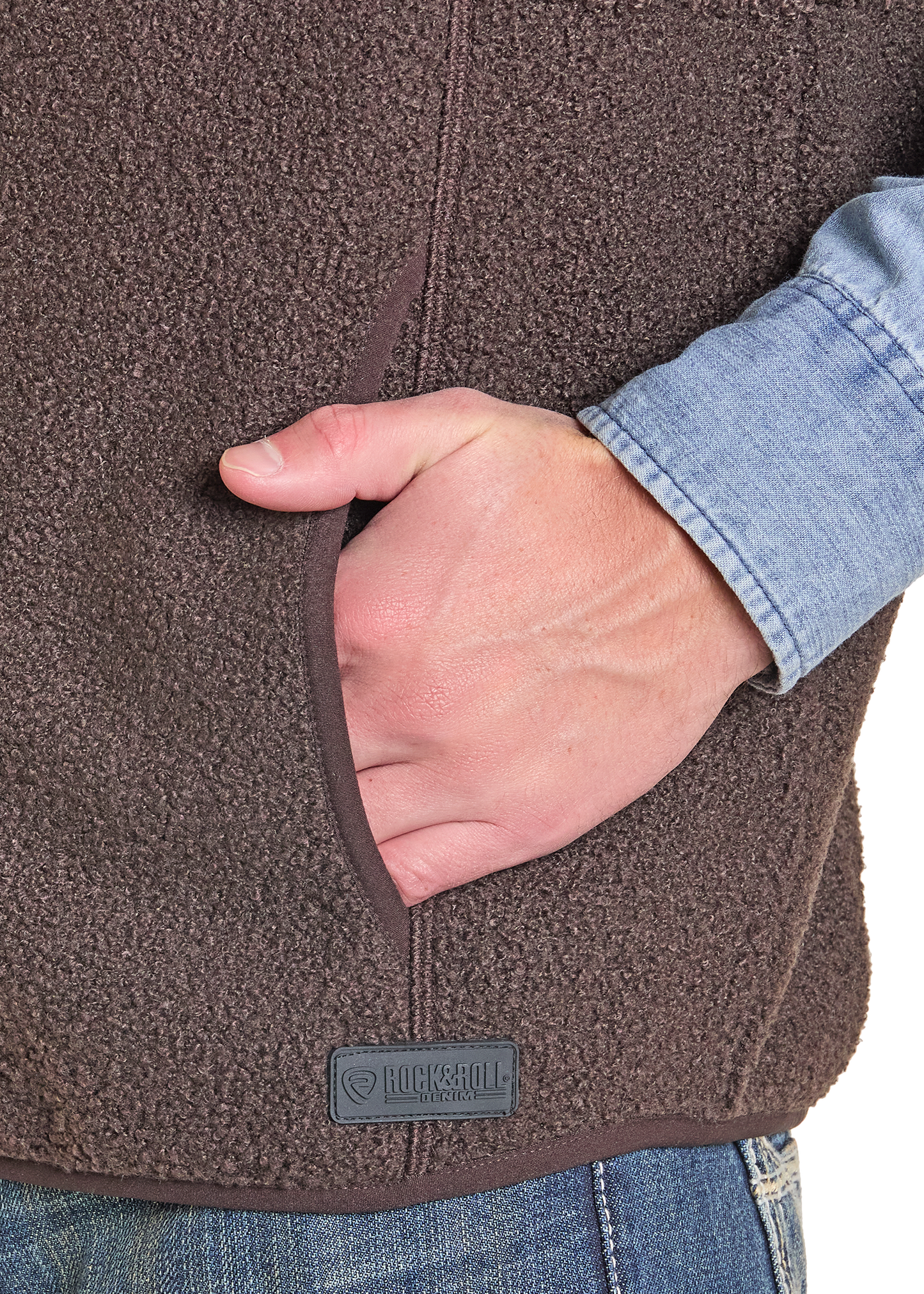 Close-up of a brown fleece jacket with a hand in the pocket, featuring a brand logo.