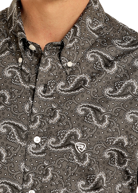A close-up of a person wearing the Rock & Roll Denim Classic Fit Paisley Print Long Sleeve Button Down Shirt, featuring a black and white paisley pattern, western button-down style, button-down collar, and white buttons.