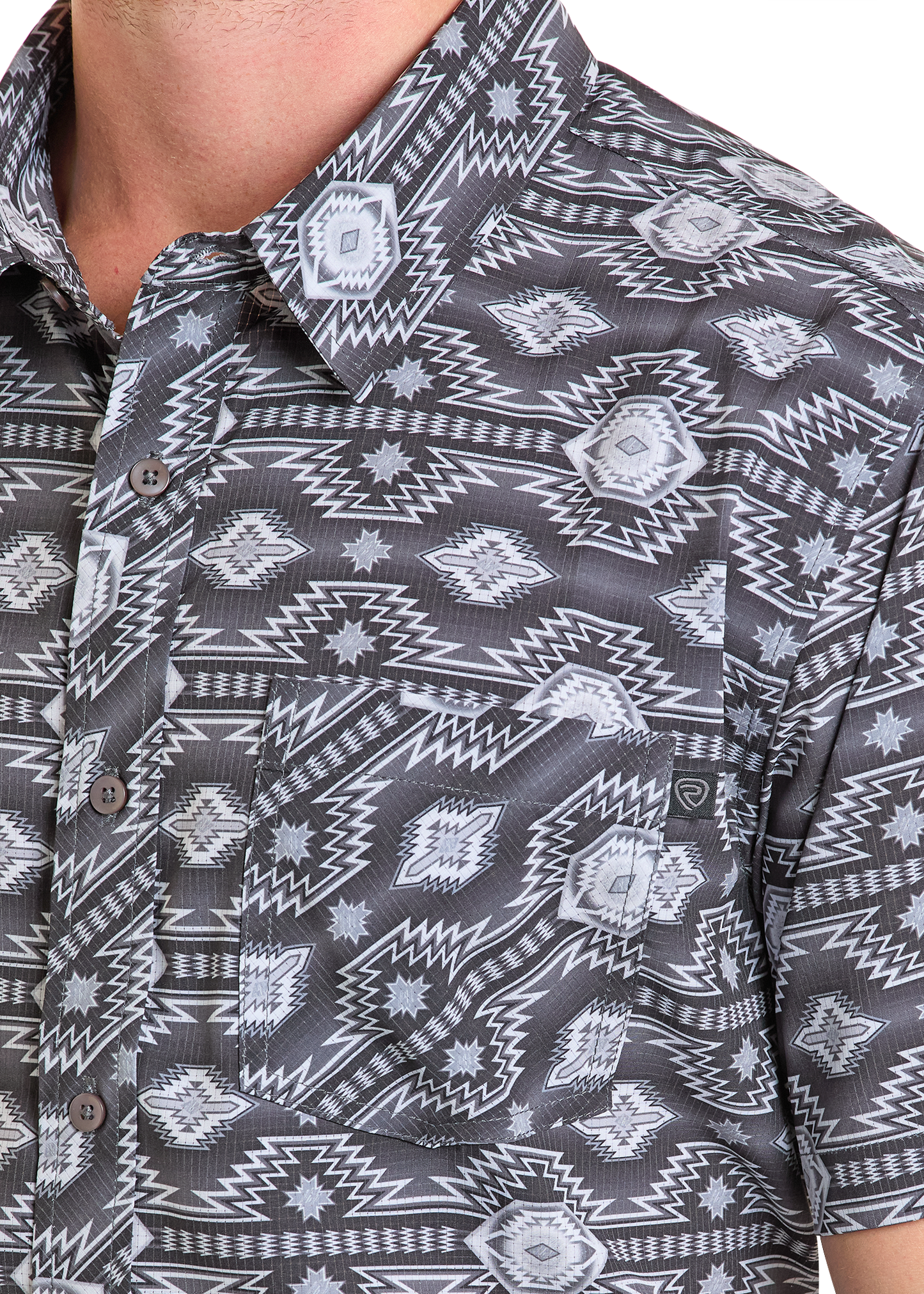 A close-up of a person wearing the Rock & Roll Denim TEK Western Short Sleeve Aztec Print Shirt, featuring a black, white, and gray geometric pattern, chest pocket, visible buttons, collar, and UPF 50 protection.