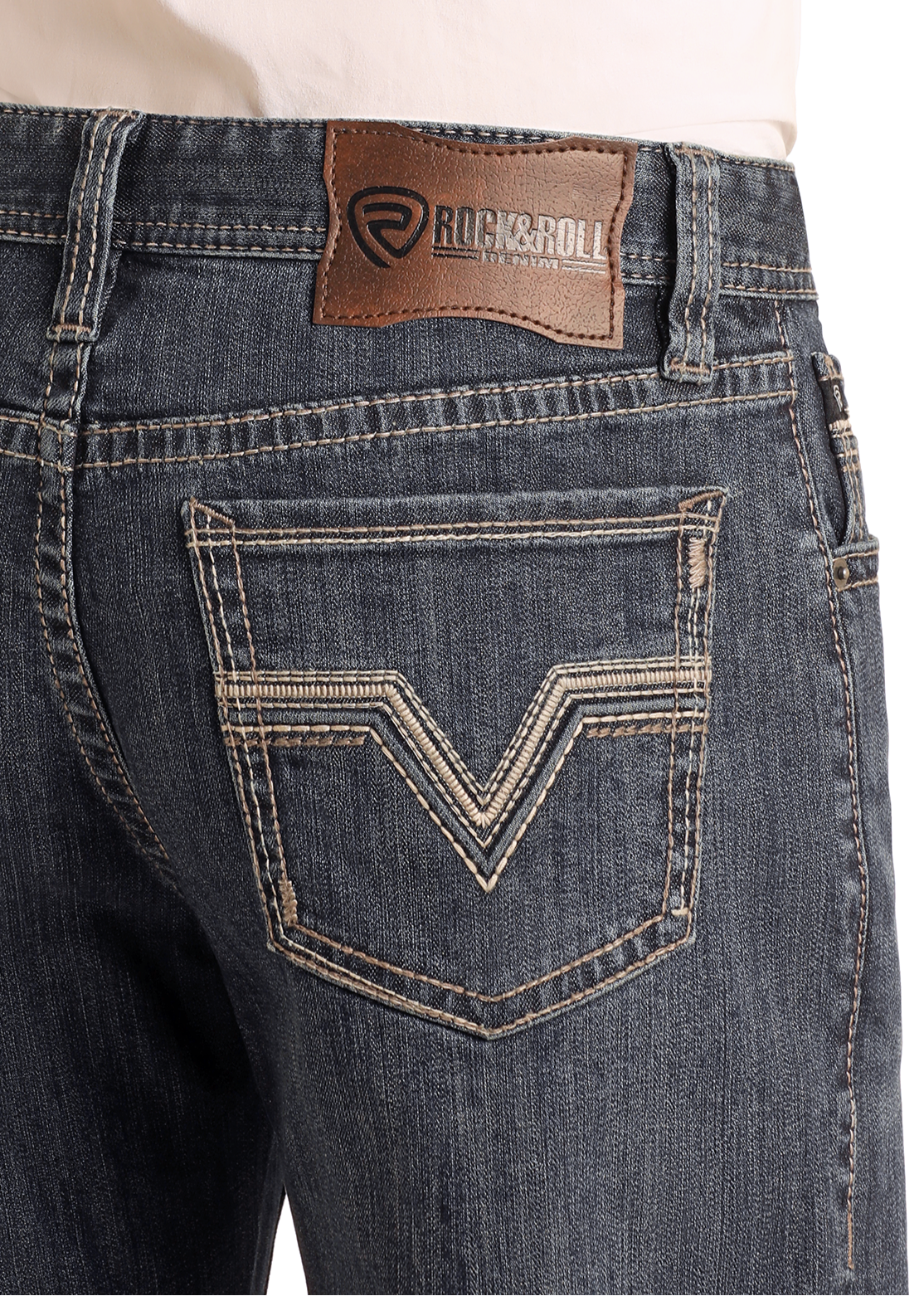 Close-up of the back of a person wearing Rock & Roll Denim High Rise Relaxed Fit Alpha Stackable Bootcut Jeans with tan stitching, two back pockets with decorative details, and a brown leather brand patch on the waistband.