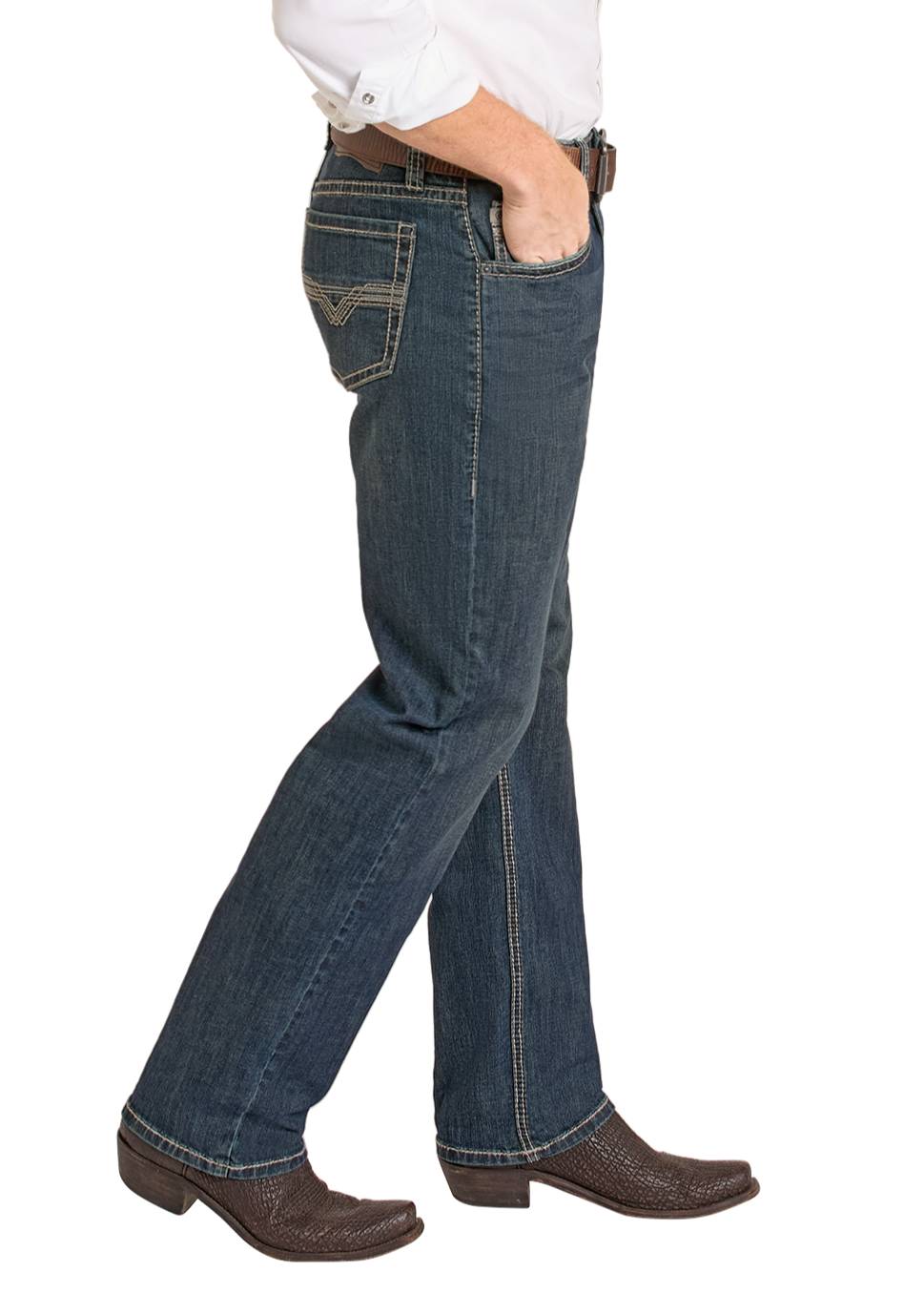 A person models Rock & Roll Denim High Rise Relaxed Fit Alpha Tapered Bootcut Jeans in dark blue, paired with a white shirt, brown belt, and brown cowboy boots, posing side view with one hand in their pocket against a white background.
