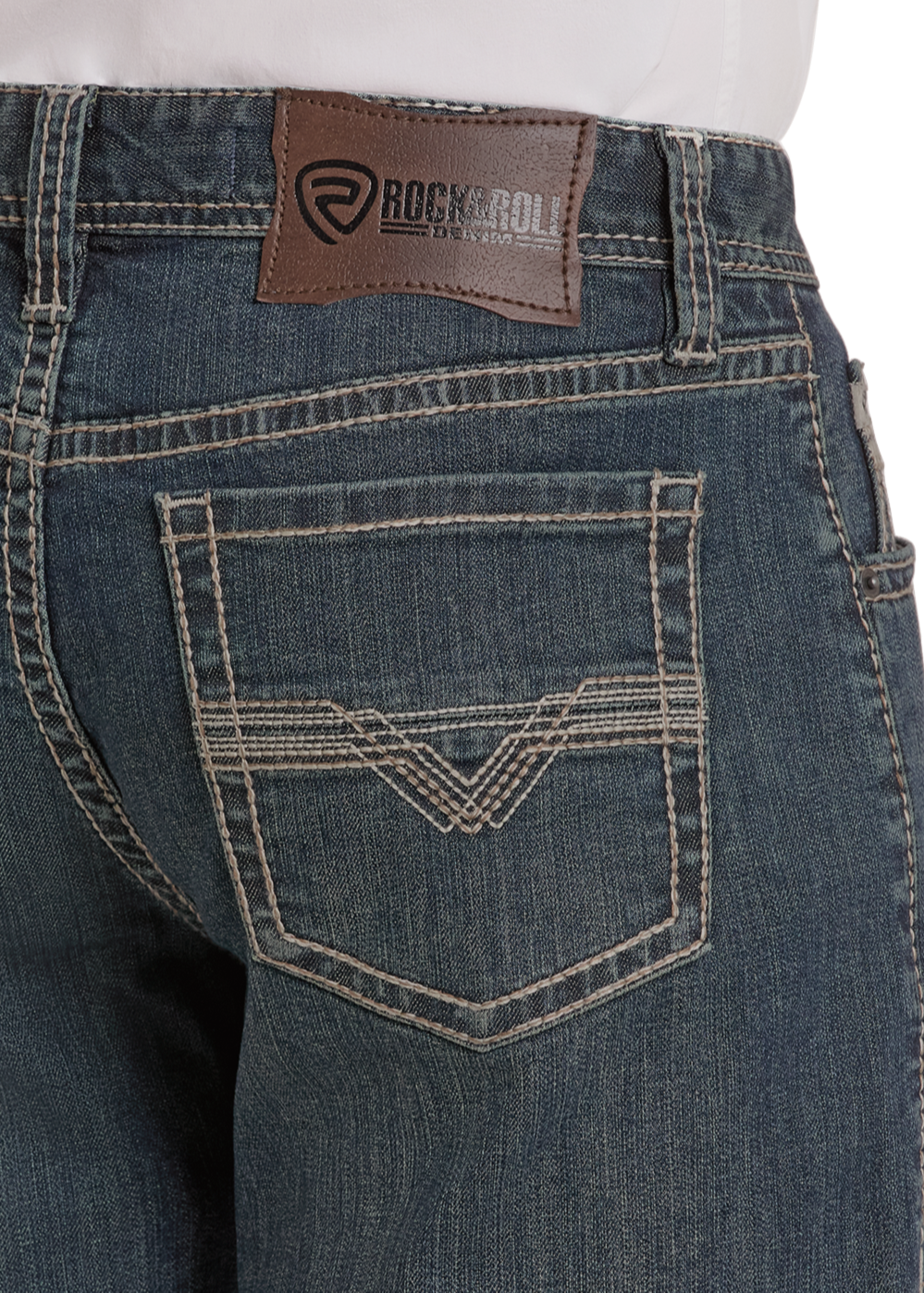 Close-up of High Rise Relaxed Fit Alpha Tapered Bootcut Jeans by Rock & Roll Denim, showing white stitching, a brown leather waistband patch with the brand name, and decorative stitched back pockets.