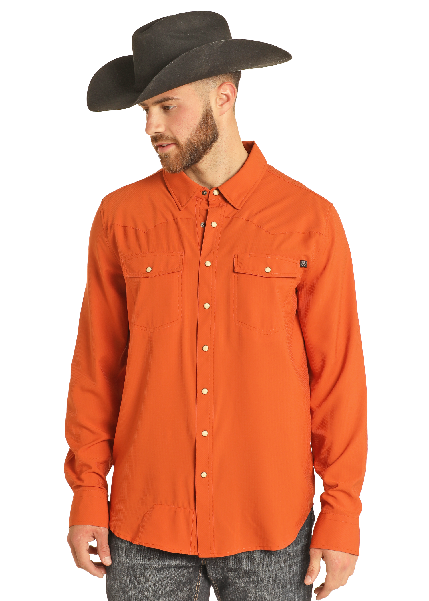 A man wears the Rock & Roll Denim TEK Western Burnt Orange Long Sleeve Shirt and a wide-brimmed black cowboy hat, looking down and to the side against a plain white background.