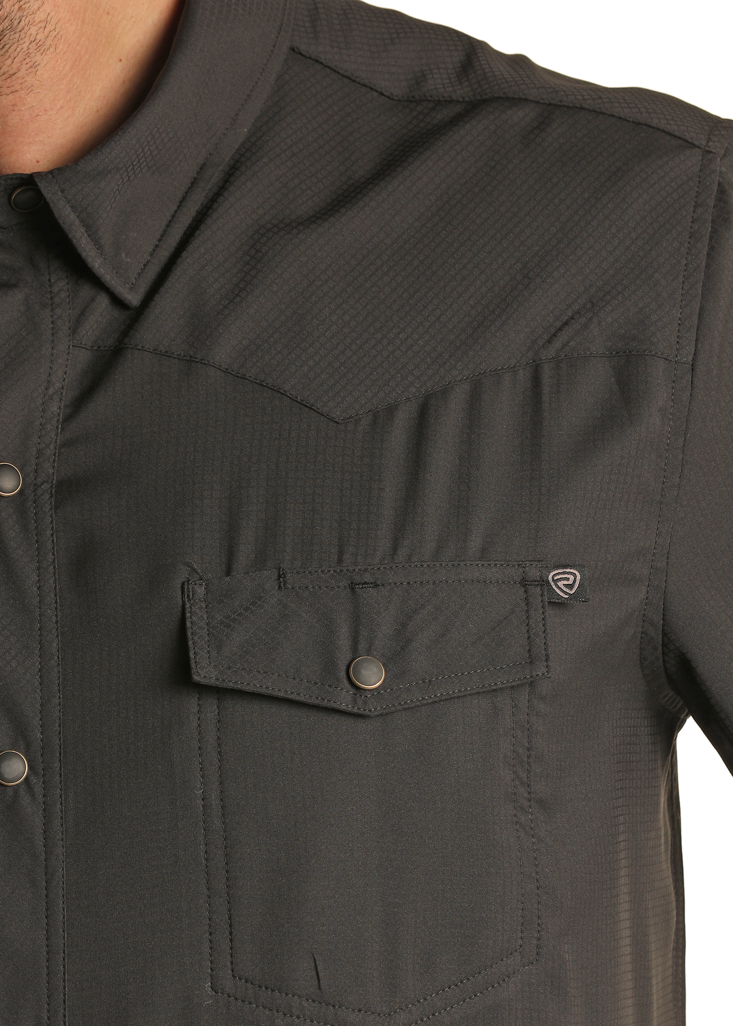 Close-up of a person wearing the Rock & Roll Denim TEK Western Black Long Sleeve Shirt, featuring a front pocket with a small logo tag, metal snap buttons, and visible collar and shoulder.