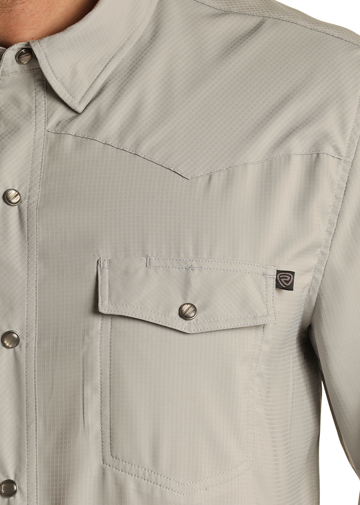 Close-up of the Rock & Roll Denim TEK Western Grey Long Sleeve Shirt—featuring a pointed collar, snap buttons, front chest pocket with black logo tag, and moisture-wicking fabric. Only the upper torso is shown.