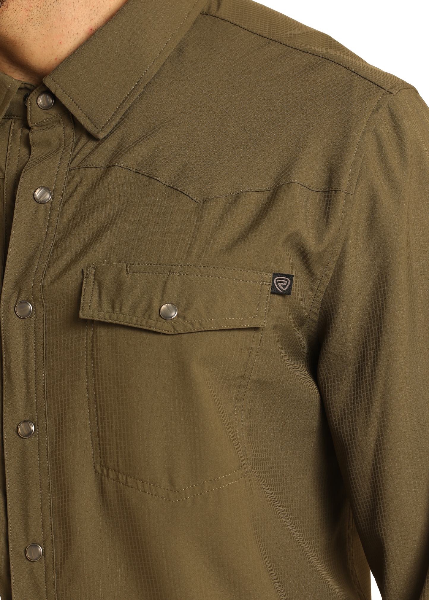 Close-up of a person wearing the Rock & Roll Denim TEK Western Olive Long Sleeve Shirt, featuring a front chest pocket with metal snaps and a black logo tag. Only the upper torso and part of the left arm are visible.