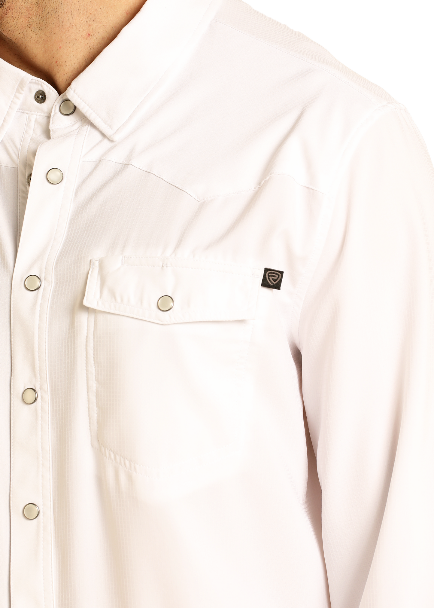 A close-up of a person wearing the Rock & Roll Denim TEK Western White Long Sleeve Shirt, showing snap buttons, a chest pocket with a small black logo tag above it, and UPF 50 protection. Only the upper torso and part of the neck are visible.